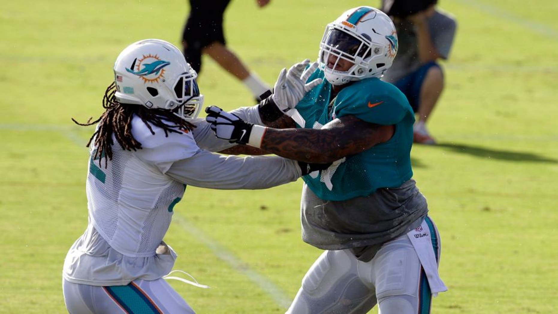 Miami Dolphins center Mike Pouncey, right, and linebacker Kelvin Sheppard, left, do drills during an NFL football training camp practice, Sunday, Aug. 16, 2015, in Davie, Fla. (AP Photo/Lynne Sladky)