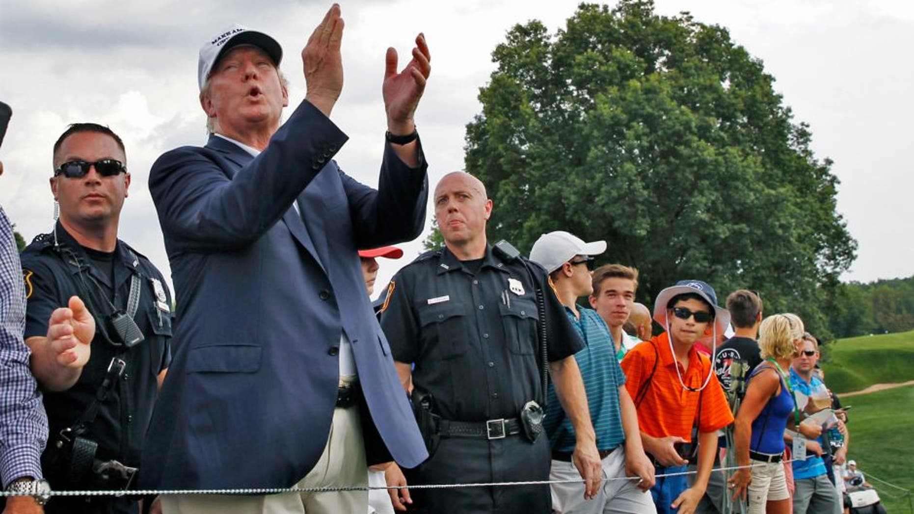 Republican presidential candidate Donald Trump, second left, applauds play as he walks with a crowd during the final round of play at The Barclays golf tournament Sunday, Aug. 30, 2015, in Edison, N.J. (AP Photo/Mel Evans)