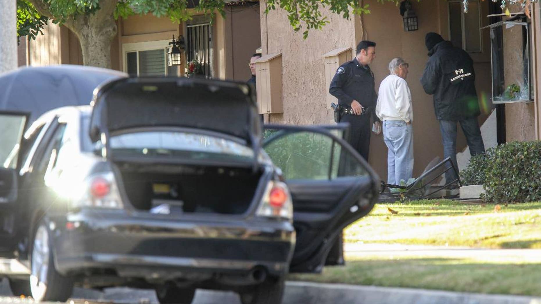 FBI agents interview a man, center, outside a home in connection to the shootings in San Bernardino, Thursday, Dec. 3, 2015, in Redlands, Calif. A heavily armed man and woman opened fire Wednesday on a holiday banquet for his co-workers, killing multiple people and seriously wounding others in a precision assault, authorities said. Hours later, they died in a shootout with police. (AP Photo/Ringo H.W. Chiu)
