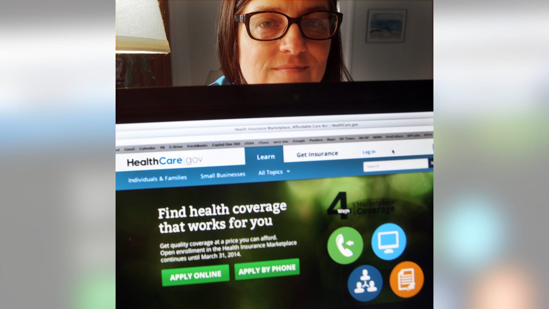 In a photo taken Monday Oct. 28, 2013, in Portsmouth, N.H., Deborah Lielasus poses behind her computer with the national health insurance enrollment website. Not long after she enrolled, the Department of Health and Human Services asked her to appear both in a video describing her experience and in photographs that could replace the stock photo on the insurance enrollment site. (AP Photo/Jim Cole)