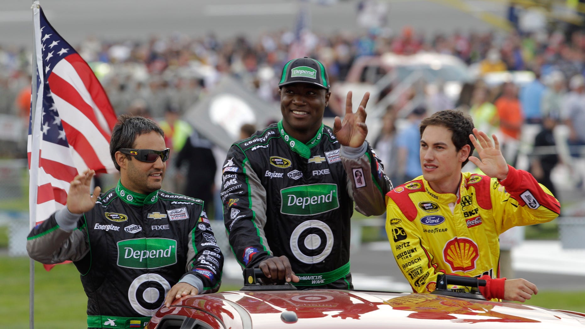 Dallas Cowboys NFL football player DeMarcus Ware, center, waves to the crowd along with drivers Juan Pablo Montoya, left, and Joey Logano, right, prior to the Toyota Owner's 400 NASCAR Sprint Cup series auto race at Richmond International Raceway in Richmond, Va., Saturday April 27, 2013. (AP Photo/Steve Helber)