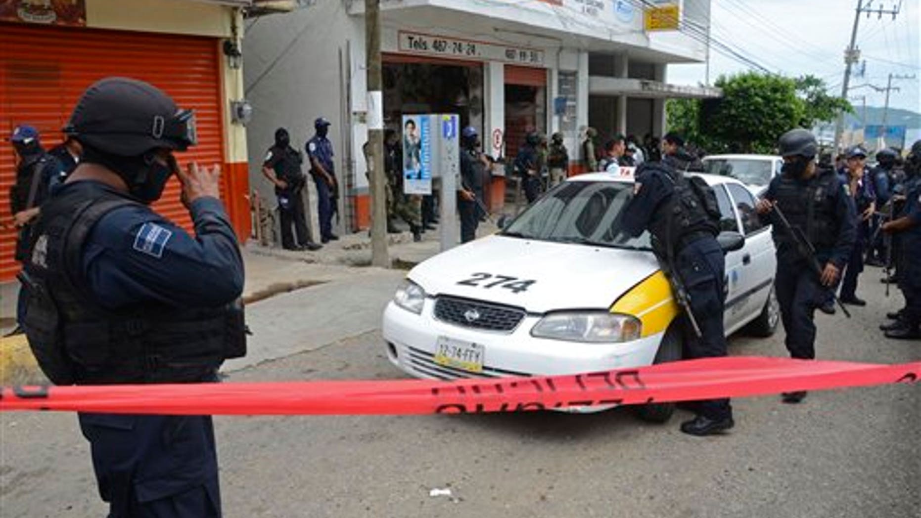 Federal police inspect a taxi in the Pacific resort city of Acapulco, Mexico, Saturday July 16, 2011. Two men with multiple gunshot wounds with their hands tied behind their backs were found inside the vehicle's trunk.