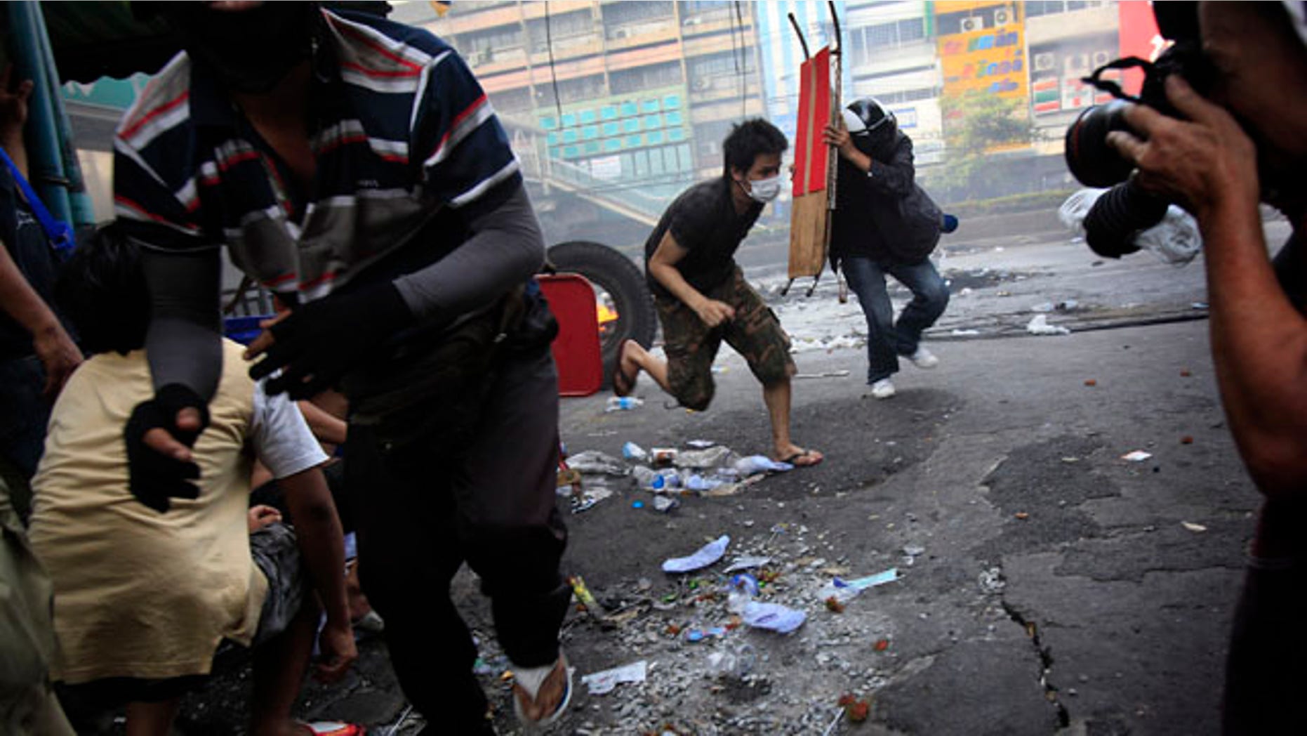 Anti-government protesters run for cover as Thai soldiers fire shots at them at an intersection on Saturday May 15, 2010 in Bangkok, Thailand.