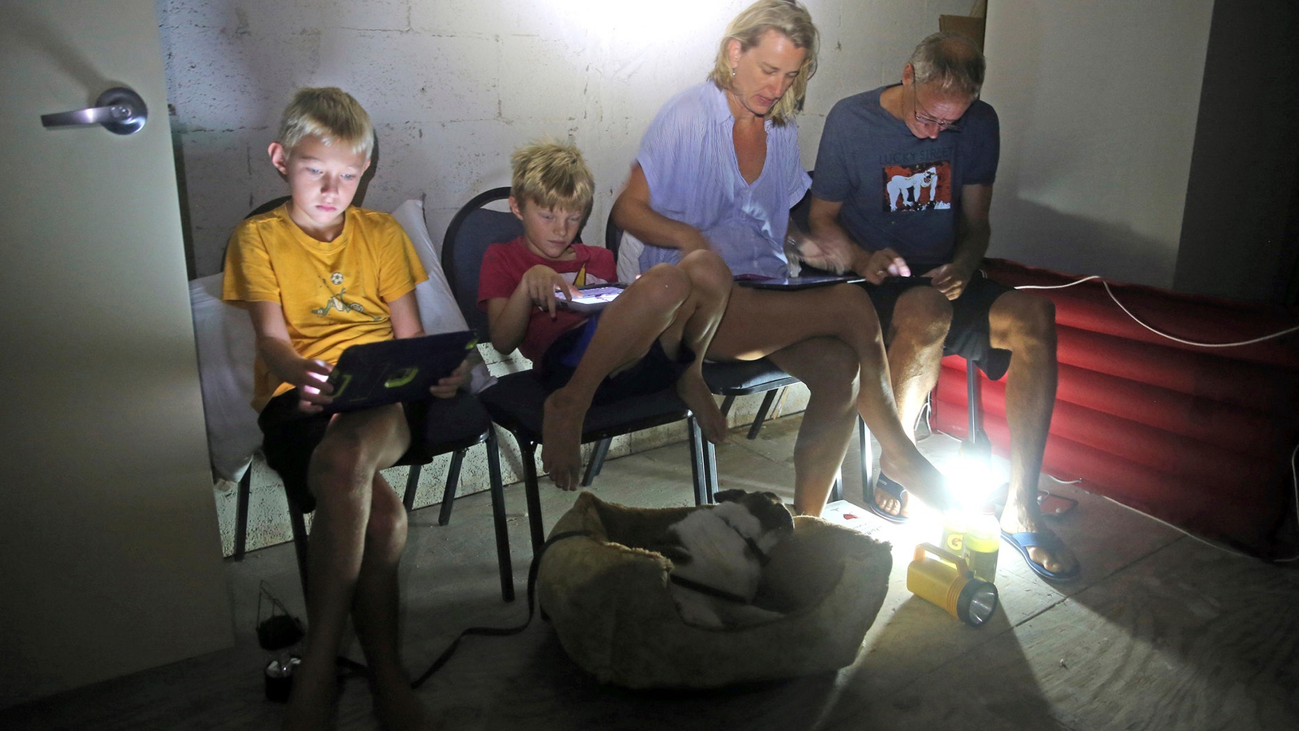 The Blinckman family use their personal devices while sheltering in a stairwell utility closet as Hurricane Irma goes over Key West, Fla., Sunday, Sept. 10, 2017. Hurricane Irma made landfall near Cudjoe Key as a Category 4 hurricane. (Charles Trainor Jr/The Miami Herald via AP)