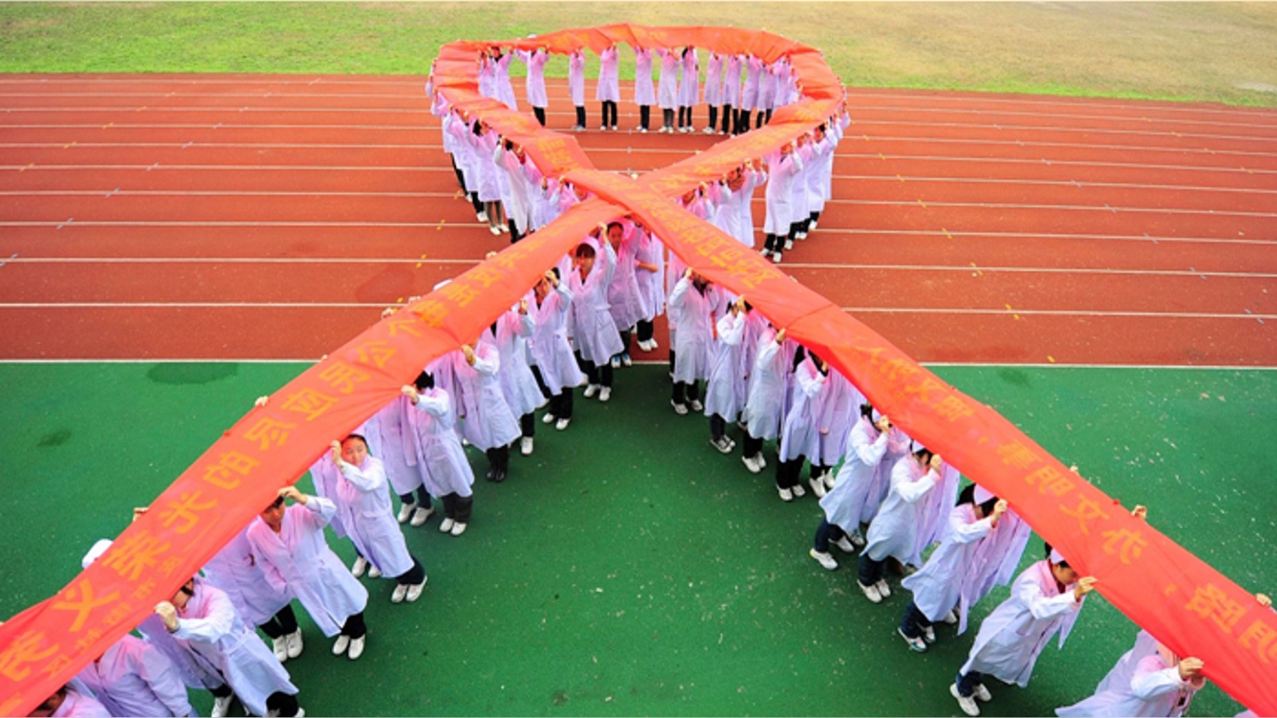 Nurses stand to form a Red Ribbon while holding a banner to mark World AIDS Day at a medical school in Yangzhou, Jiangsu province.