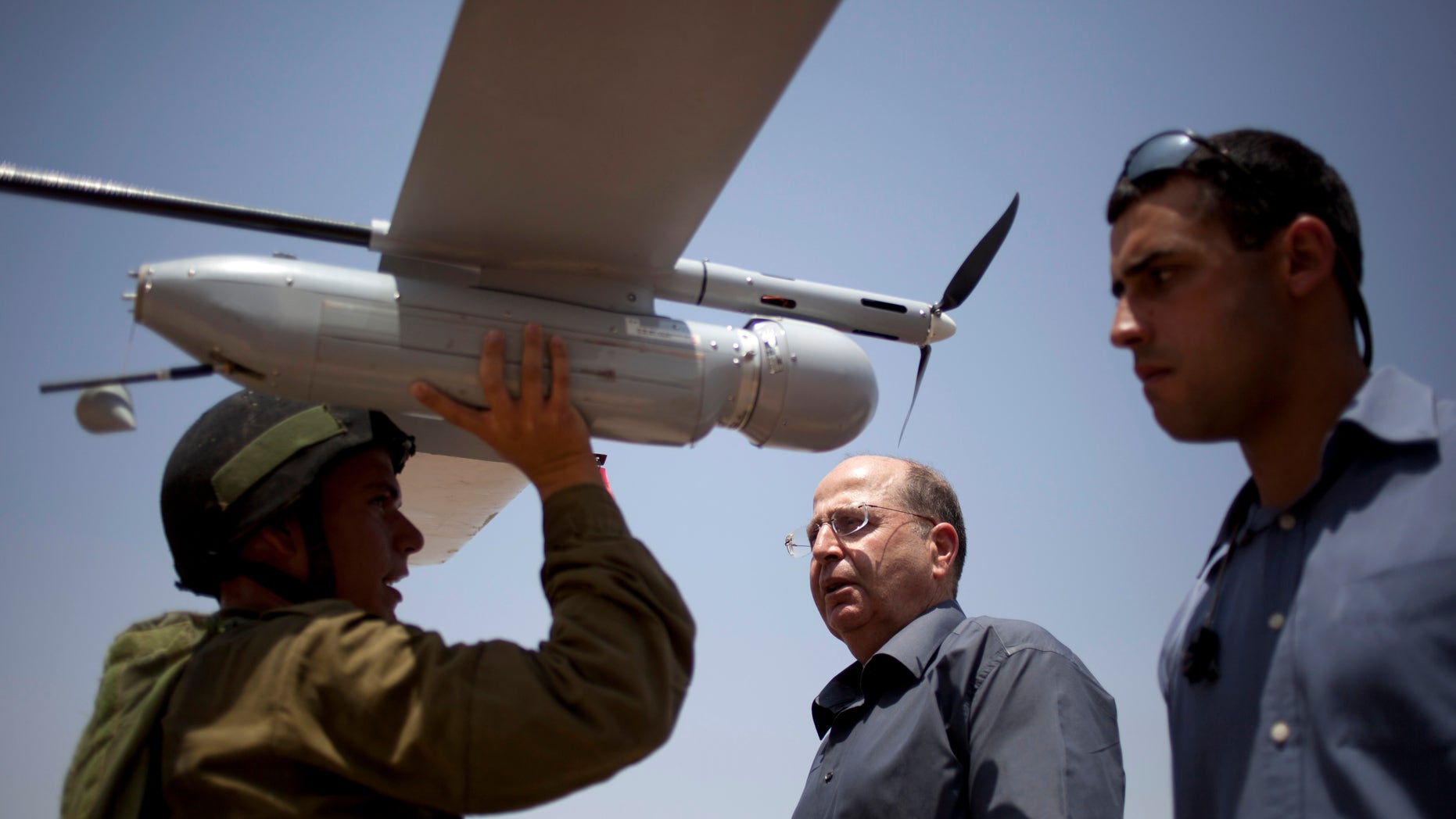 File - In this July 9, 2013 file photo, an Israeli soldier holds up a Skylark I (Rochev Shamayim) unmanned drone as part of a demonstration for Israel's Defense Minister Moshe Yaalon, center, in an urban warfare army training facility, near Zeelim, southern Israel. Yaalon said Tuesday Dec. 3, 2013, that Israel is transferring food, including baby food, as well as water and other “basic needs” to Syria. (AP Photo/Ariel Schalit, File)