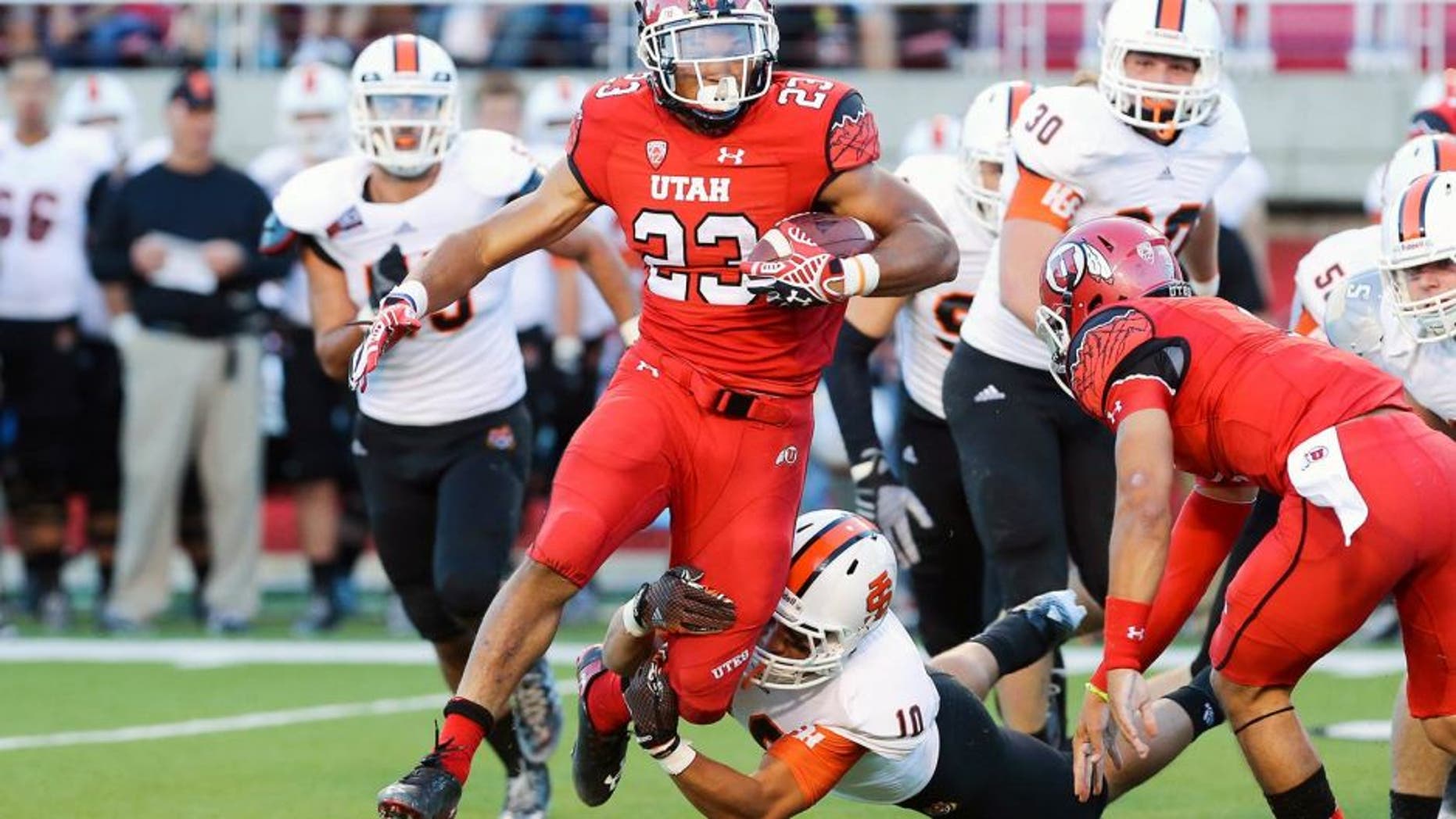 Aug 28, 2014; Salt Lake City, UT, USA; Utah Utes running back Devontae Booker (23) carries the ball as Idaho State Bengals defensive back Taison Manu (10) chases during the third quarter at Rice-Eccles Stadium. The Utes won 56-14. Mandatory Credit: Chris Nicoll-USA TODAY Sports