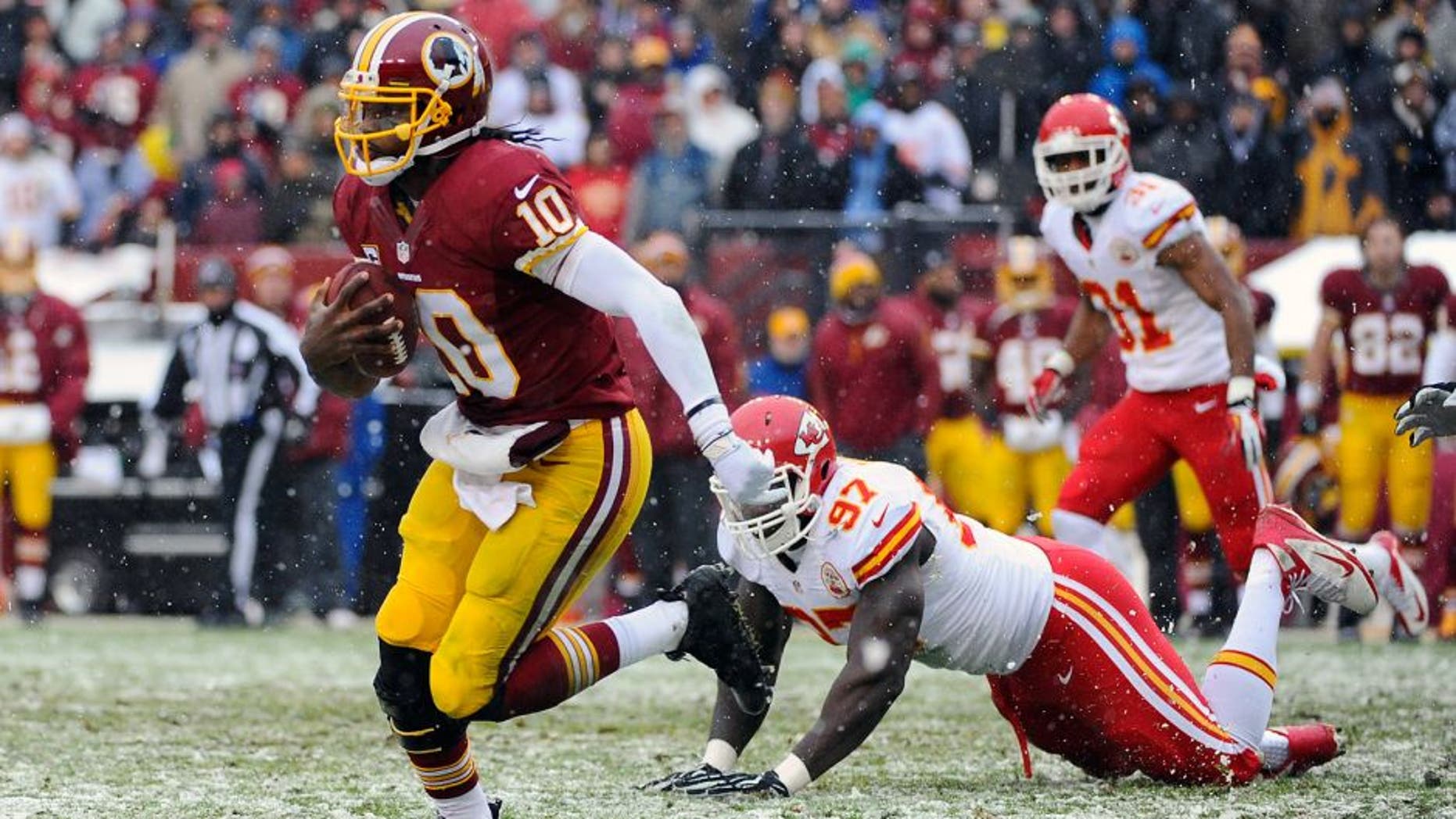 Dec 8, 2013; Landover, MD, USA; Washington Redskins quarterback Robert Griffin III (10) avoids the tackle by Kansas City Chiefs defensive end Allen Bailey (97) during the second quarter at FedEx Field. Mandatory Credit: Brad Mills-USA TODAY Sports