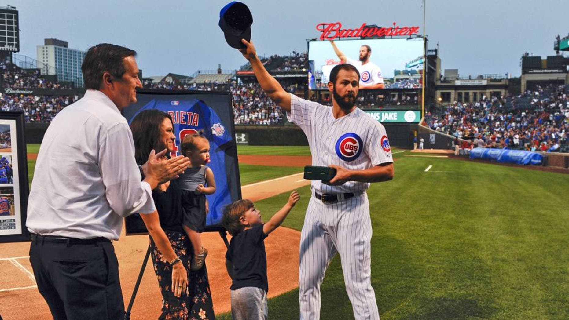 Aug 31, 2015; Chicago, IL, USA; Chicago Cubs starting pitcher Jake Arrieta (49), acknowledges the crowd while standing with his family, Cooper (son) and Palmer (daughter), Brittany Arrieta, his wife, and Chicago Cubs owner Tom Ricketts before the game against the Cincinnati Reds at Wrigley Field. Arrieta pitched a no-hitter the night before in Los Angeles. Mandatory Credit: Matt Marton-USA TODAY Sports