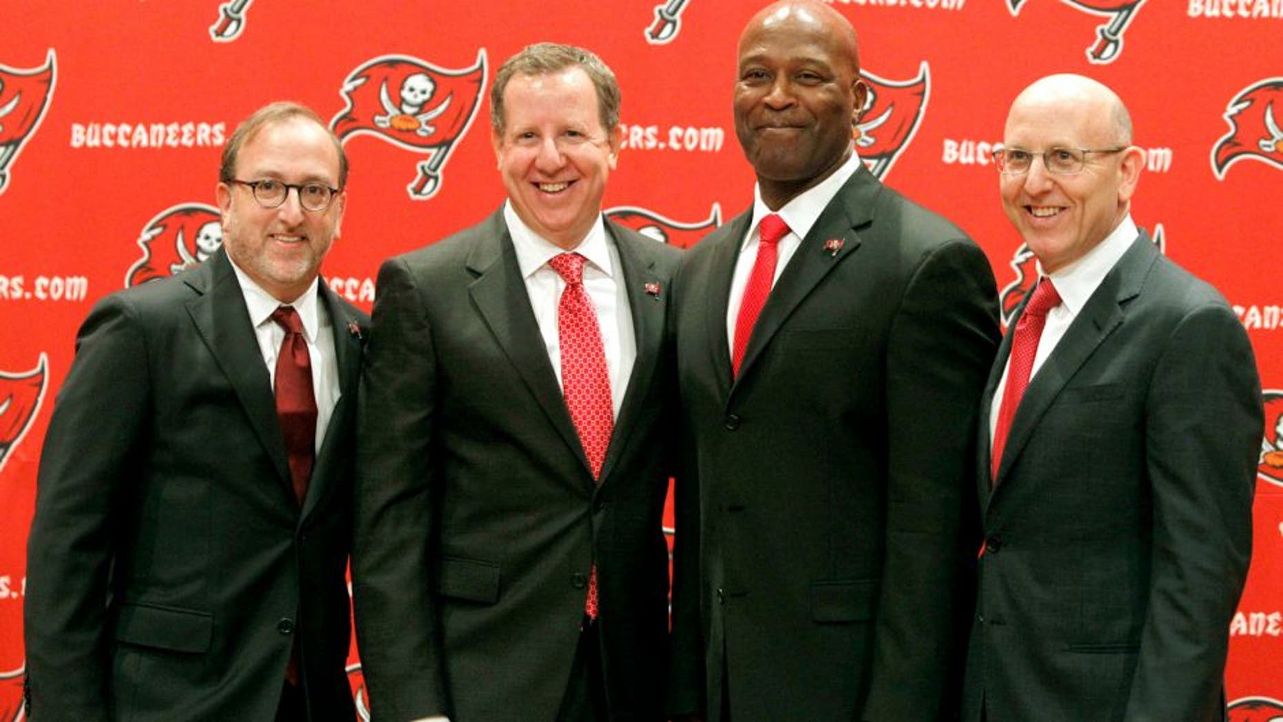 Jan 6, 2014; Tampa, FL, USA; Tampa Bay Buccaneers head coach Lovie Smith (second from right) poses with owners from left Edward Glazer , Bryan Glazer and Joel Glazer during a press conference at One Buccaneer Place. Mandatory Credit: Kim Klement-USA TODAY Sports