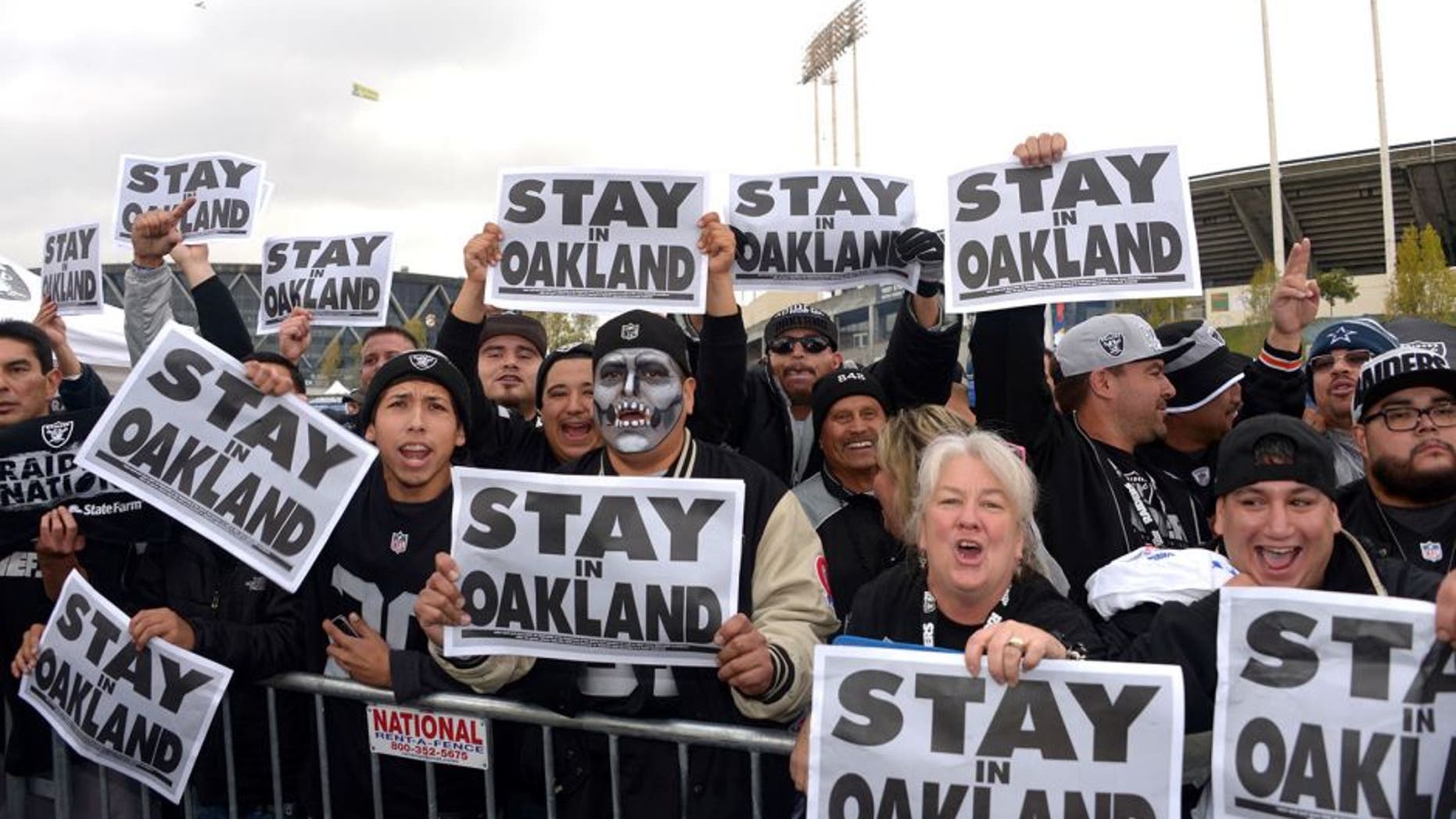 Nov 20, 2014; Oakland, CA, USA; Oakland Raiders fans tailgate while holding signs the read "Stay in Oakland" before the NFL football game against the Kansas City Chiefs at O.co Coliseum. Mandatory Credit: Kirby Lee-USA TODAY Sports