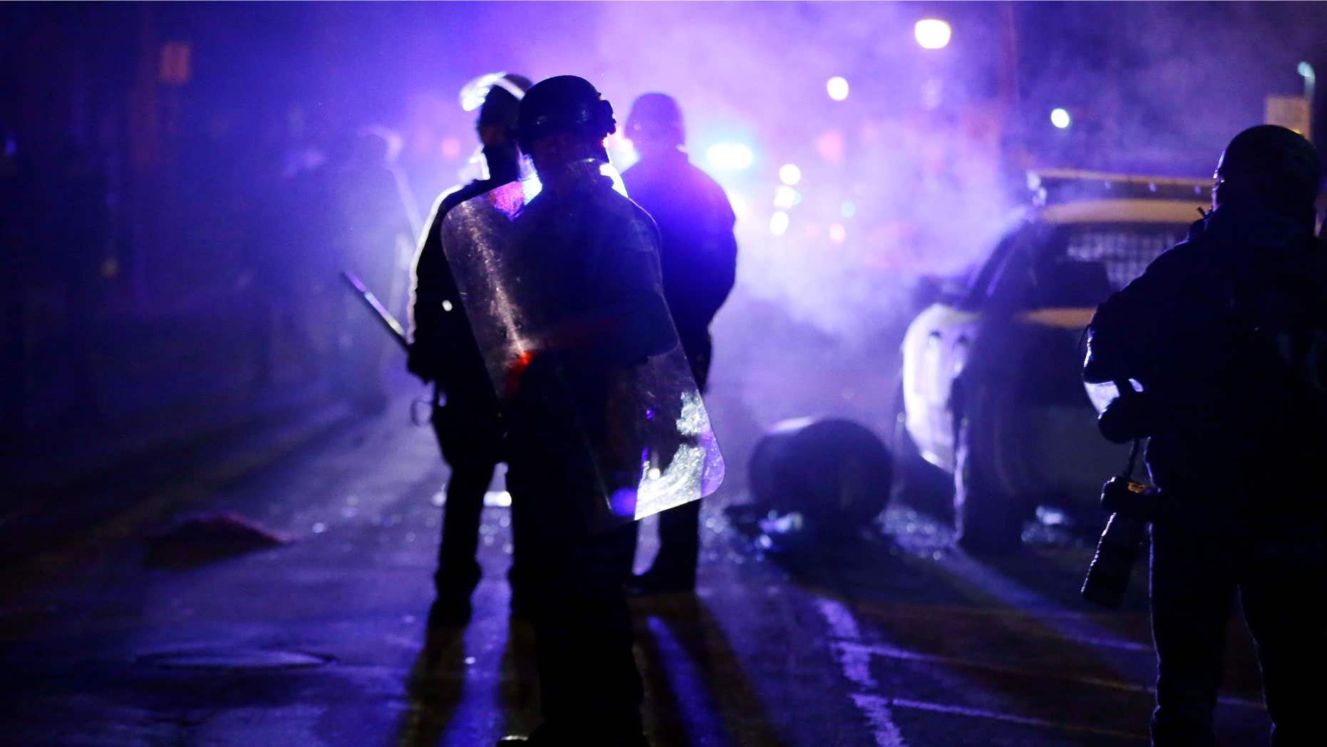 Nov. 25, 2014: Police officers watch protesters as smoke fills the streets in Ferguson, Mo. after a grand jury's decision in the fatal shooting of Michael Brown.