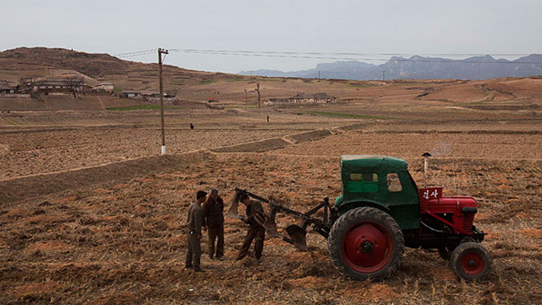 In this Tuesday, April 17, 2011 file photo, men check a plow and tractor in a field along the highway near the southern city of Kaesong, south of Pyongyang, North Korea.