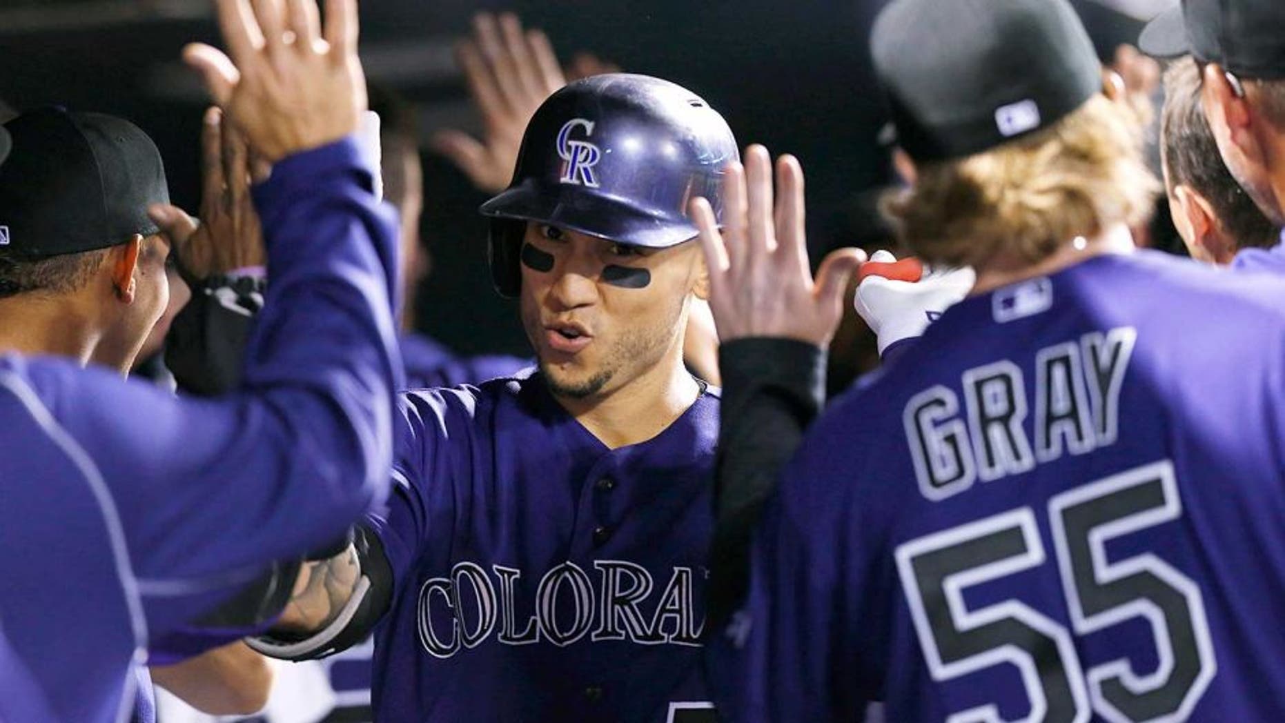 Colorado Rockies' Carlos Gonzalez, center, is congratulated by teammates as he returns to the dugout after hitting a two-run home run off San Francisco Giants relief pitcher George Kontos in the fourth inning of a baseball game, Thursday, Sept.. 3, 2015, in Denver. (AP Photo/David Zalubowski)