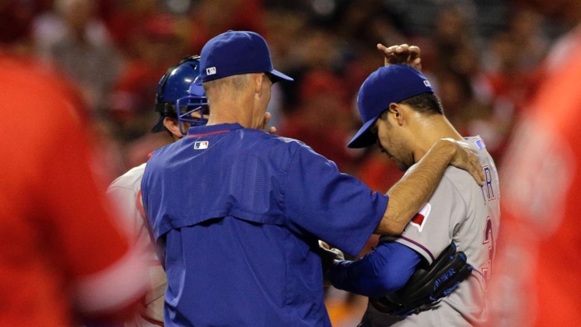 Texas Rangers pitching coach Mike Maddux, center, confers with starting pitcher Martin Perez, center right, and catcher Bobby Wilson after Perez walked Los Angeles Angels' Albert Pujols, foreground right, during the third inning of a baseball game, Friday, Sept. 4, 2015, in Anaheim, Calif. (AP Photo/Jae C. Hong)
