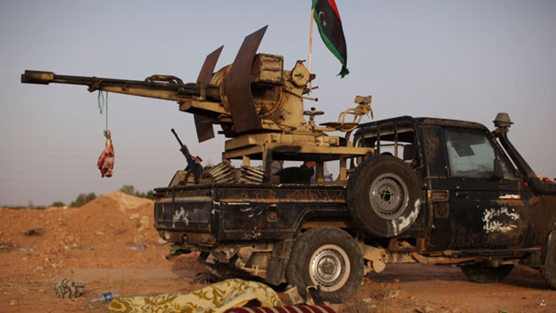 Sept. 5: A rebel fighter sleeps next to a goat's carcass hanging from an anti-aircraft gun at a checkpoint between Tarhouna and Bani Walid in Libya.