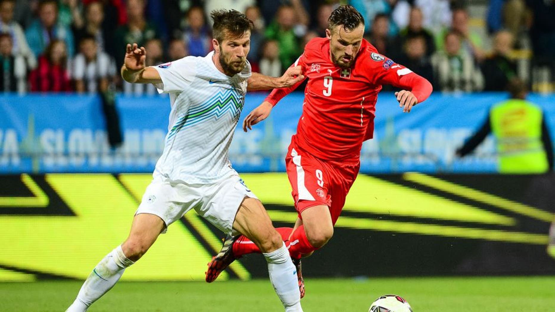 Slovenia's Bostjan Cesar (L) fights for the ball with Switzerland's Haris Seferovic on October 9, 2014 during a Euro 2016 qualifying match Slovenia vs. Switzerland in Maribor, Slovenia. AFP PHOTO / Jure Makovec (Photo credit should read Jure Makovec/AFP/Getty Images)