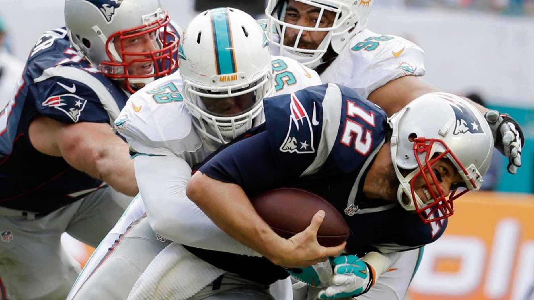 New England Patriots quarterback Tom Brady (12) is sacked by Miami Dolphins linebacker Chris McCain (58), during the second half of an NFL football game, in Miami Gardens, Fla., Sunday Sept. 7, 2014. (AP Photo/Lynne Sladky)