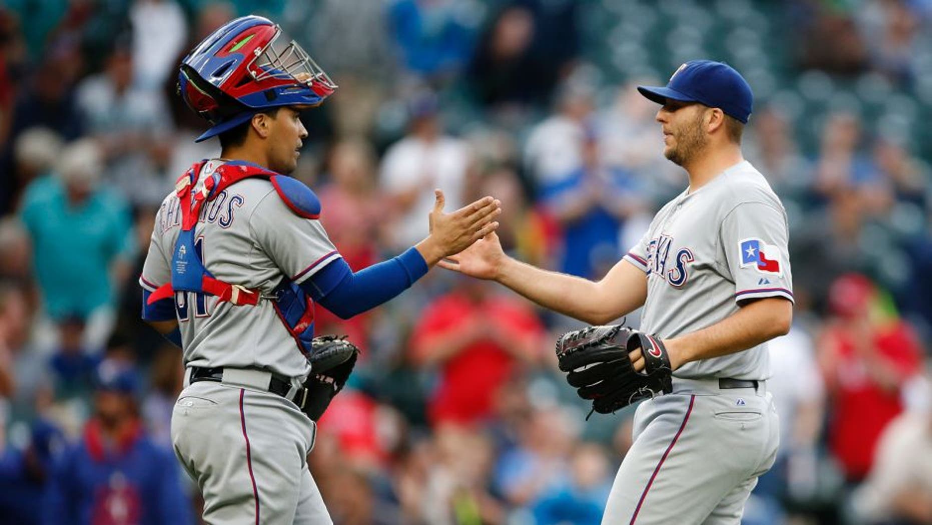 Sep 7, 2015; Seattle, WA, USA; Texas Rangers catcher Robinson Chirinos (61) and pitcher Shawn Tolleson (37) shake hands after beating the Seattle Mariners 3-0 at Safeco Field. Mandatory Credit: Jennifer Buchanan-USA TODAY Sports