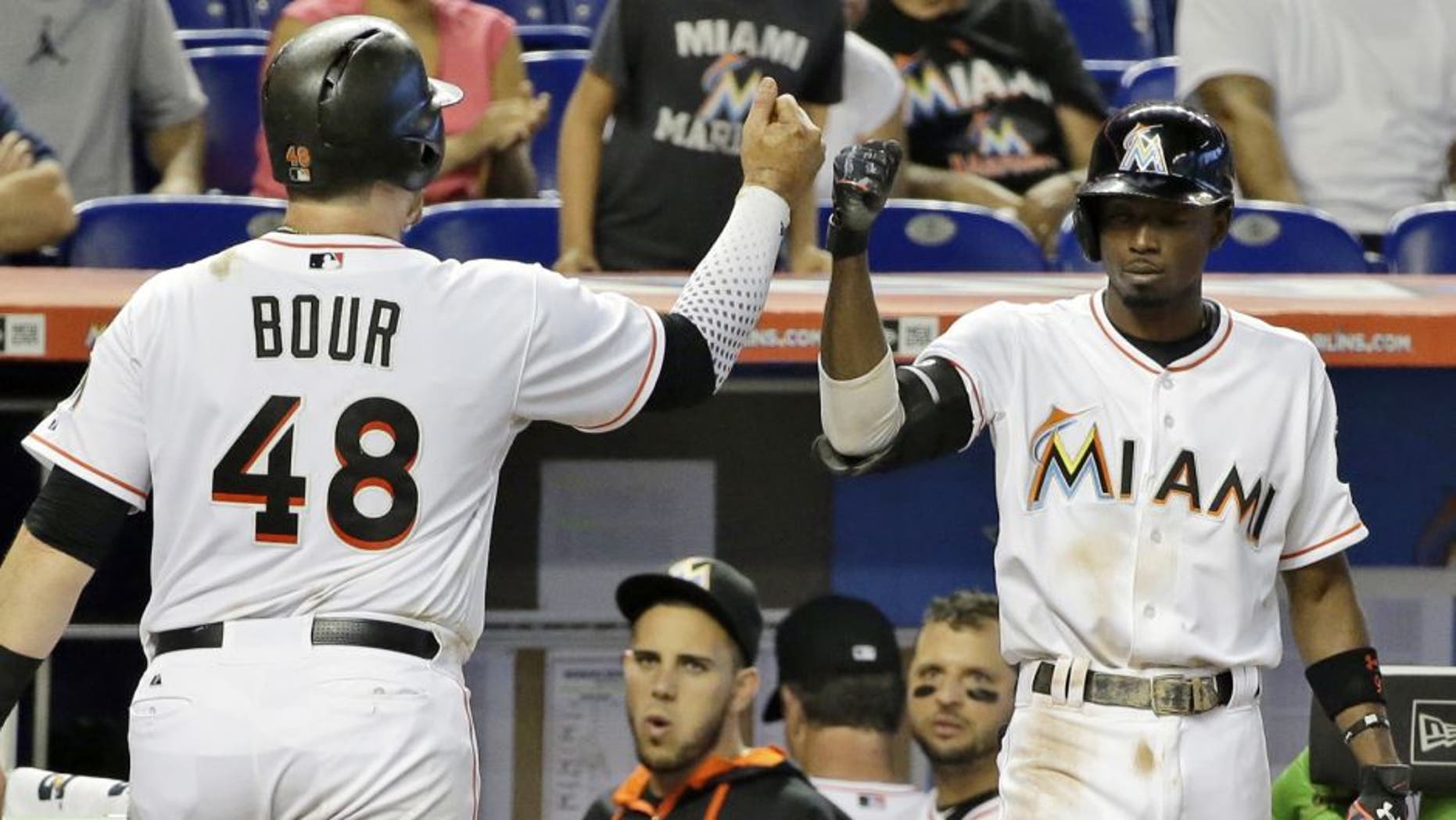Miami Marlins' Justin Bour (48) celebrates with Dee Gordon (9) after scoring after Donovan Solano hit into a double play during the fifth inning of a baseball game against the Milwaukee Brewers, Monday, Sept. 7, 2015, in Miami. (AP Photo/Wilfredo Lee)