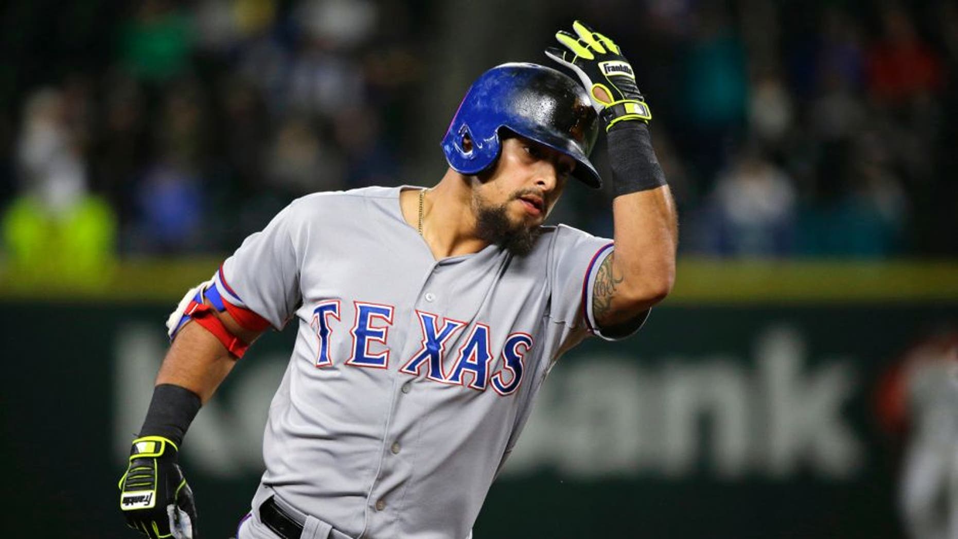 Texas Rangers' Rougned Odor holds his helmet as he rounds the bases after hitting a two-run home run against the Seattle Mariners during the fourth inning of a baseball game, Tuesday, Sept. 8, 2015, in Seattle. (AP Photo/Ted S. Warren)