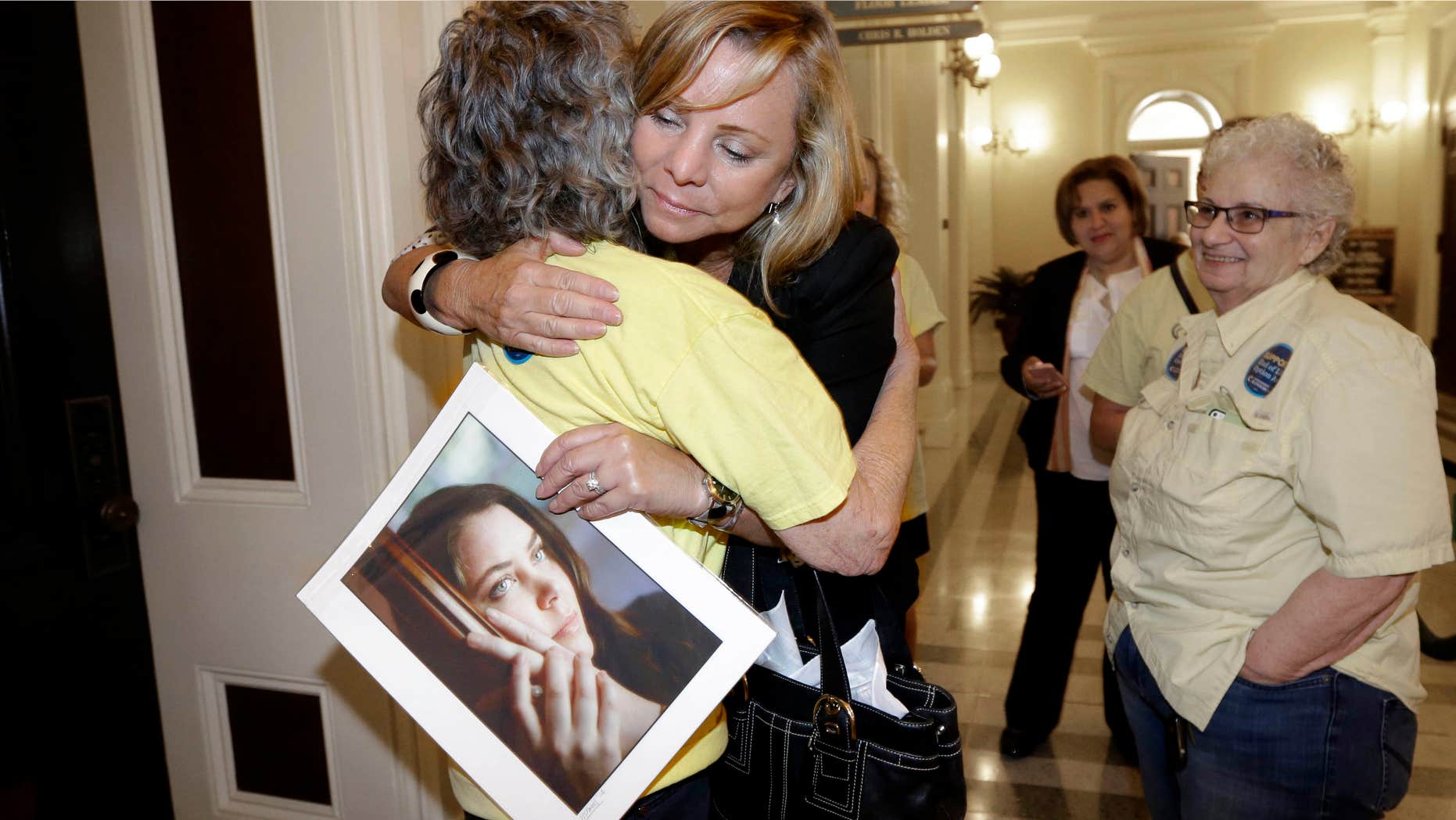 Sept. 9, 2015: Debbie Ziegler holds a photo of her daughter, Brittany Maynard, as she receives congratulations from Ellen Pontac, after a right-to die measure was approved by the Assembly in Sacramento, Calif.