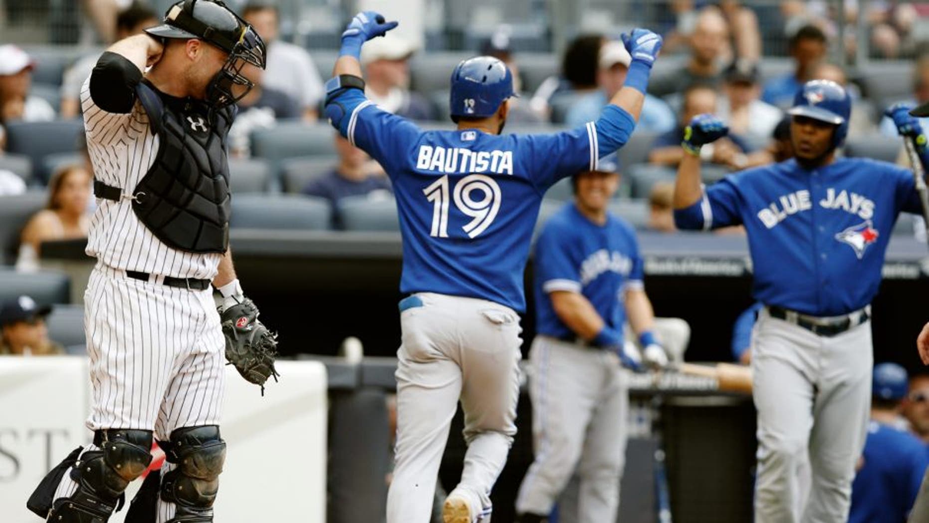 New York Yankees catcher Brian McCann, left, reacts as Toronto Blue Jays Jose Bautista (19) celebrates heading to the dugout after hitting an eighth-inning, solo, home run as on-deck-batter Edwin Encarnacion right, joins the celebration during the first baseball game of a doubleheader at Yankee Stadium in New York, Saturday, Sept. 12, 2015. (AP Photo/Kathy Willens)