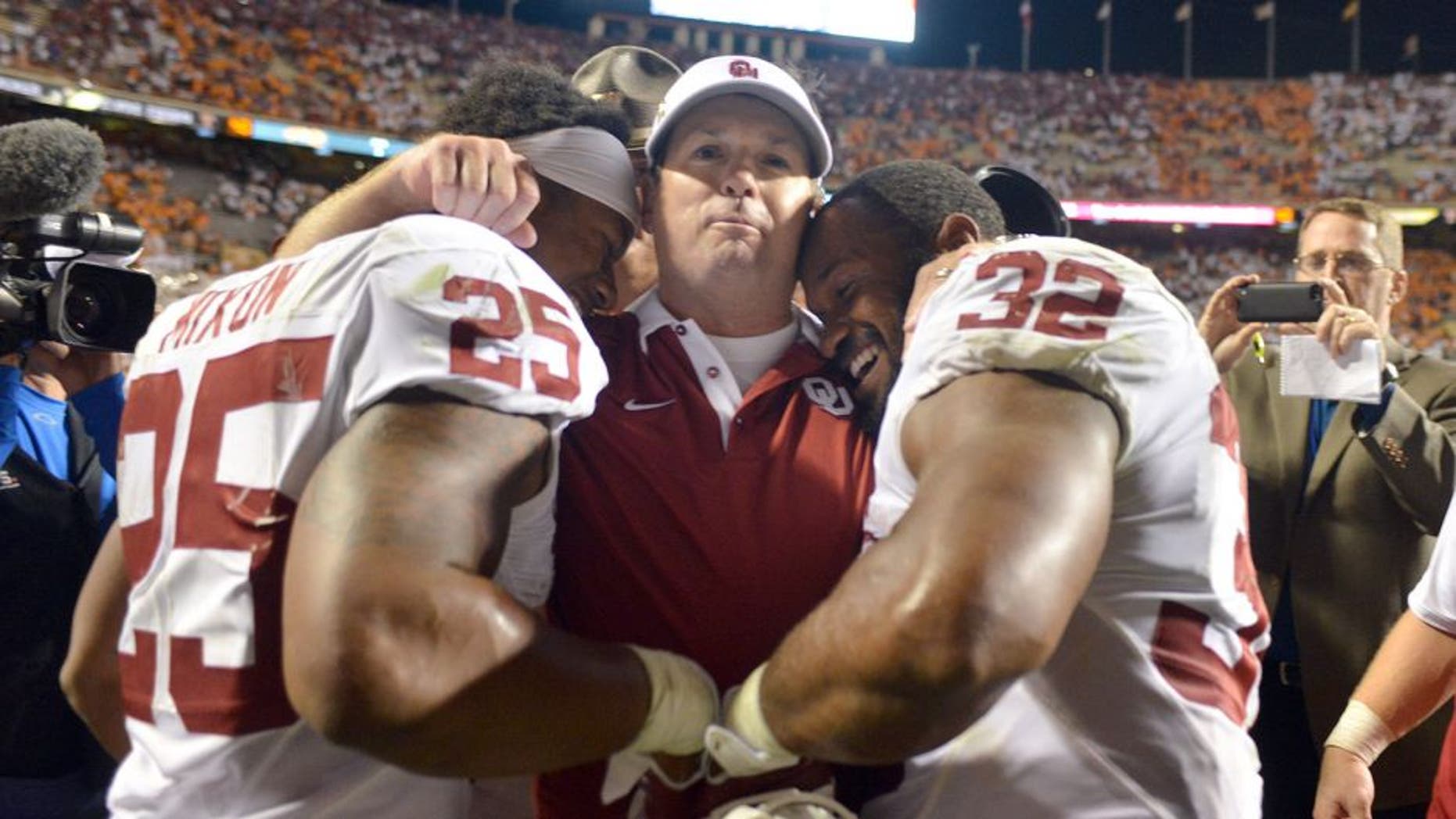 KNOXVILLE, TN - SEPTEMBER 12: Head coach Bob Stoops of the Oklahoma Sooners hugs running backs Samaje Perine #32 and Joe Mixon #25 after an overtime victory against the Tennessee Volunteers at Neyland Stadium on September 12, 2015 in Knoxville, Tennessee. (Photo by Jackson Laizure/Getty Images)
