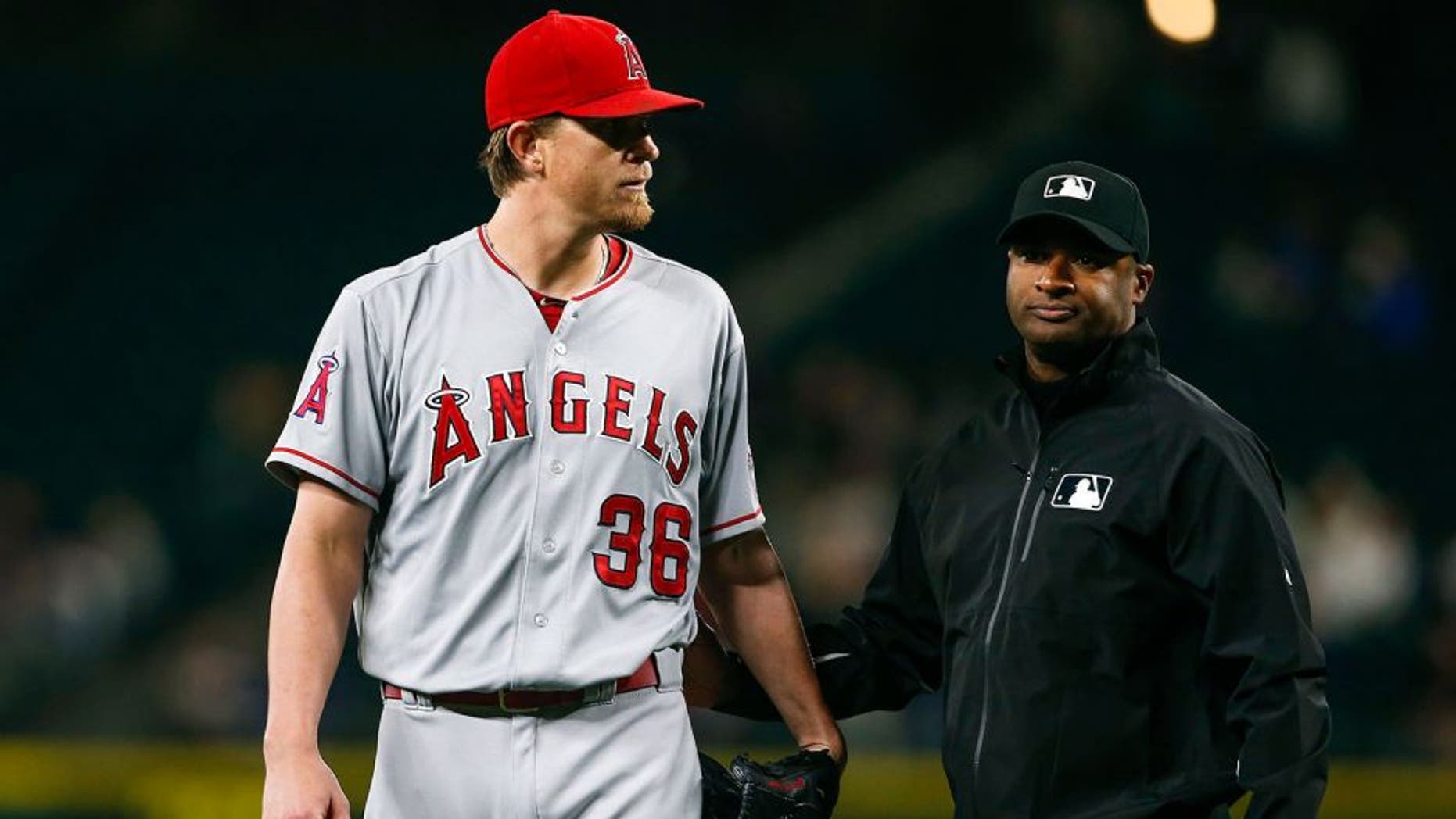 Sep 16, 2015; Seattle, WA, USA; Los Angeles Angels pitcher Jered Weaver (36) is escorted from the mound by umpire Alan Porter (64) after being ejected from the game for hitting Seattle Mariners third baseman Kyle Seager (not pictured) with a pitch during the fifth inning at Safeco Field. Mandatory Credit: Joe Nicholson-USA TODAY Sports