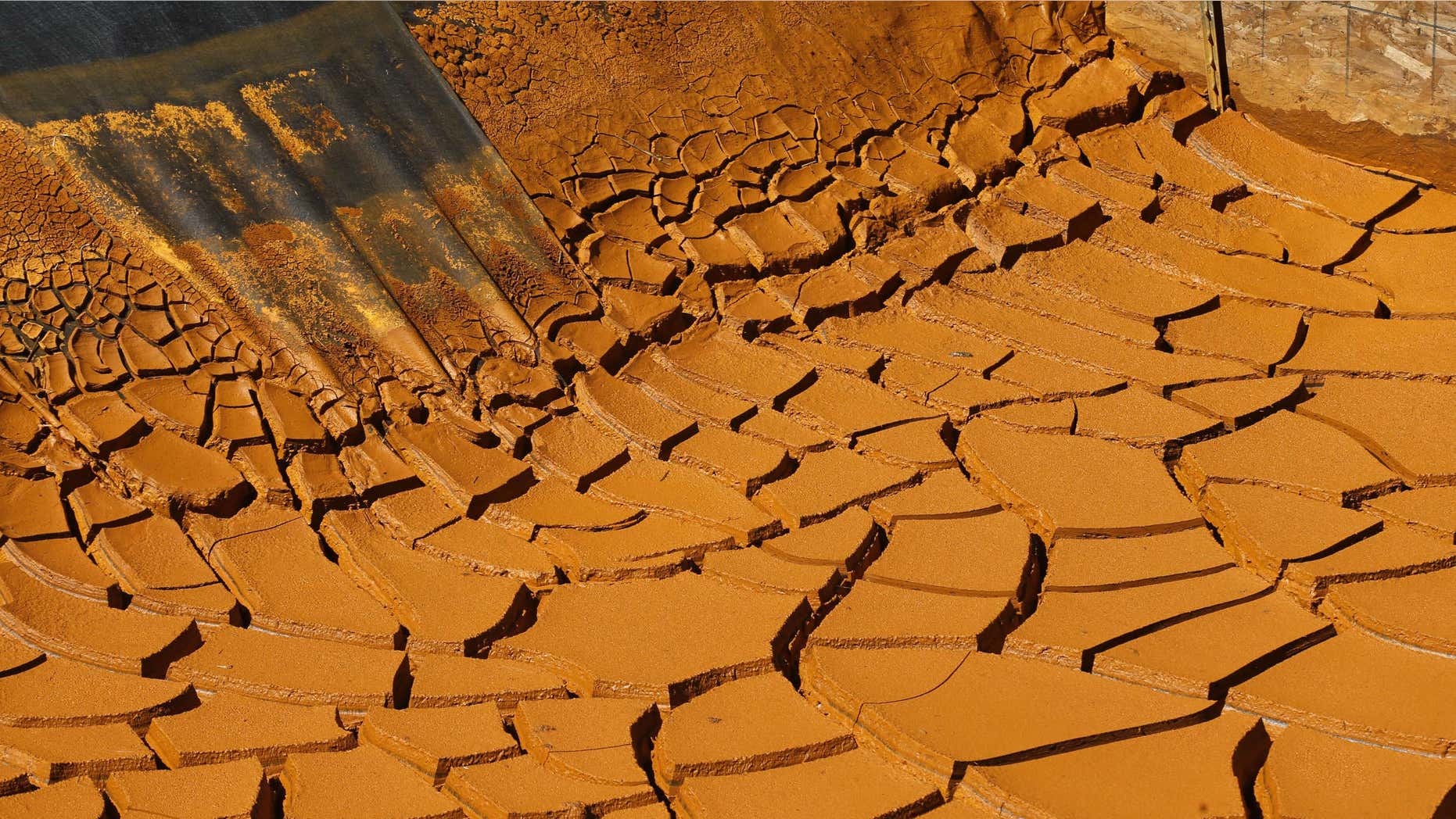 FILE - This Aug. 14, 2015, file photo, shows a dried-out mine wastewater sediment pond in the San Juan Mountains north of Silverton, Colo.