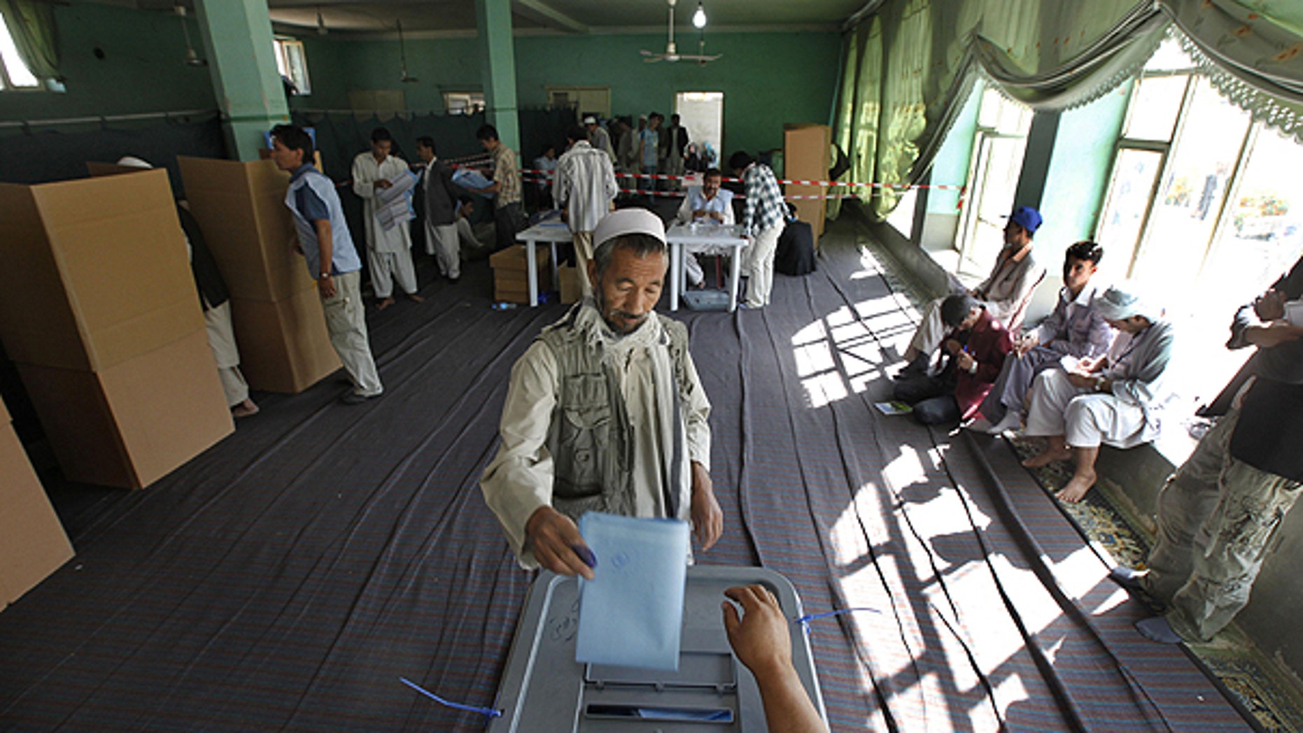Sept. 18: An Afghan man casts his ballots at a polling station as agents of candidates, right, monitor the process in Kabul, Afghanistan, during the country's parliamentary elections.