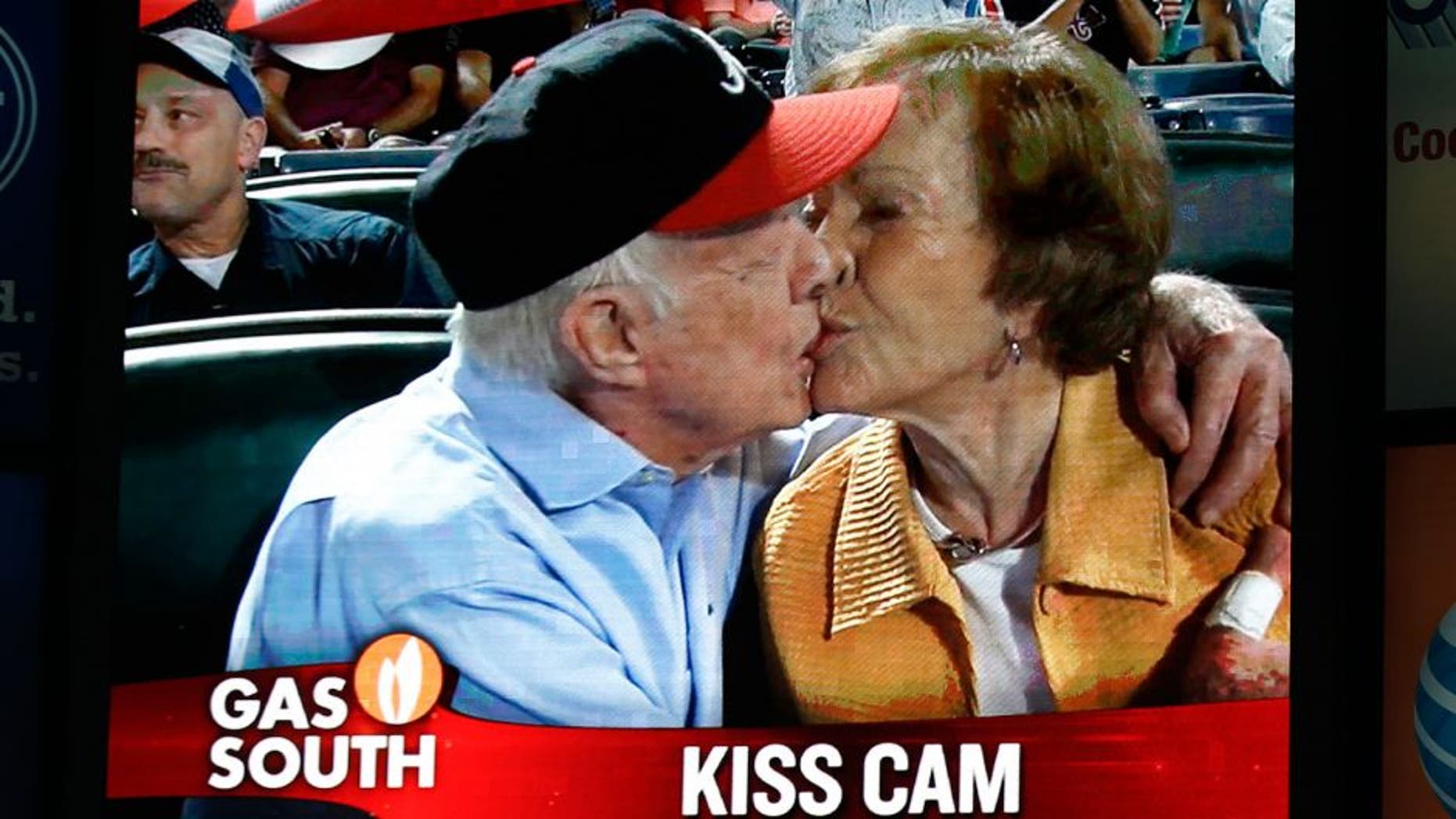Former President Jimmy Carter kisses his wife,Rosalynn, on the "Kiss Cam" during a baseball game between the Atlanta Braves and the Toronto Blue Jays on Thursday, Sept. 17, 2015, in Atlanta. Carter recently announced he has cancer. (AP Photo/John Bazemore)