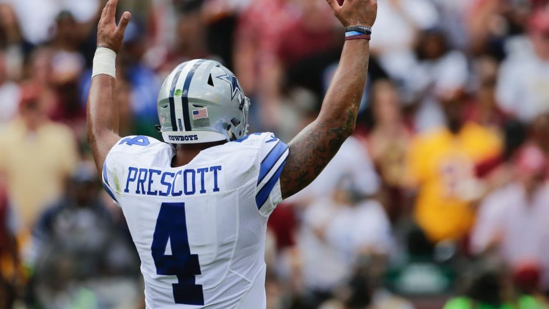 Dallas Cowboys quarterback Dak Prescott (4) celebrates running back Ezekiel Elliott's touchdown during the first half of an NFL football game against the Washington Redskins in Landover, Md., Sunday, Sept. 18, 2016. (AP Photo/Mark Tenally)