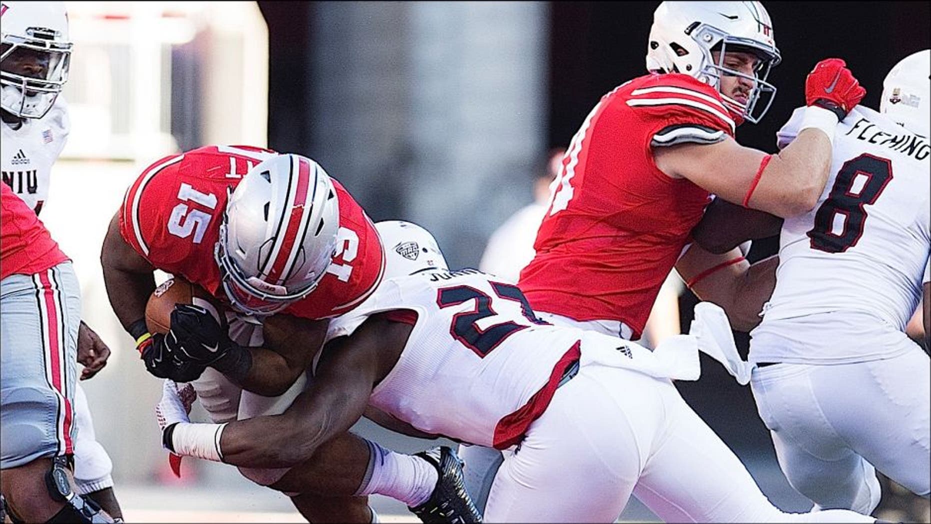 Sep 19, 2015; Columbus, OH, USA; Ohio State Buckeyes running back Ezekiel Elliott (15) is knocked off his feet by Northern Illinois Huskies safety Jawuan Johnson (27) at Ohio Stadium. Ohio State won the game 20-13. Mandatory Credit: Greg Bartram-USA TODAY Sports