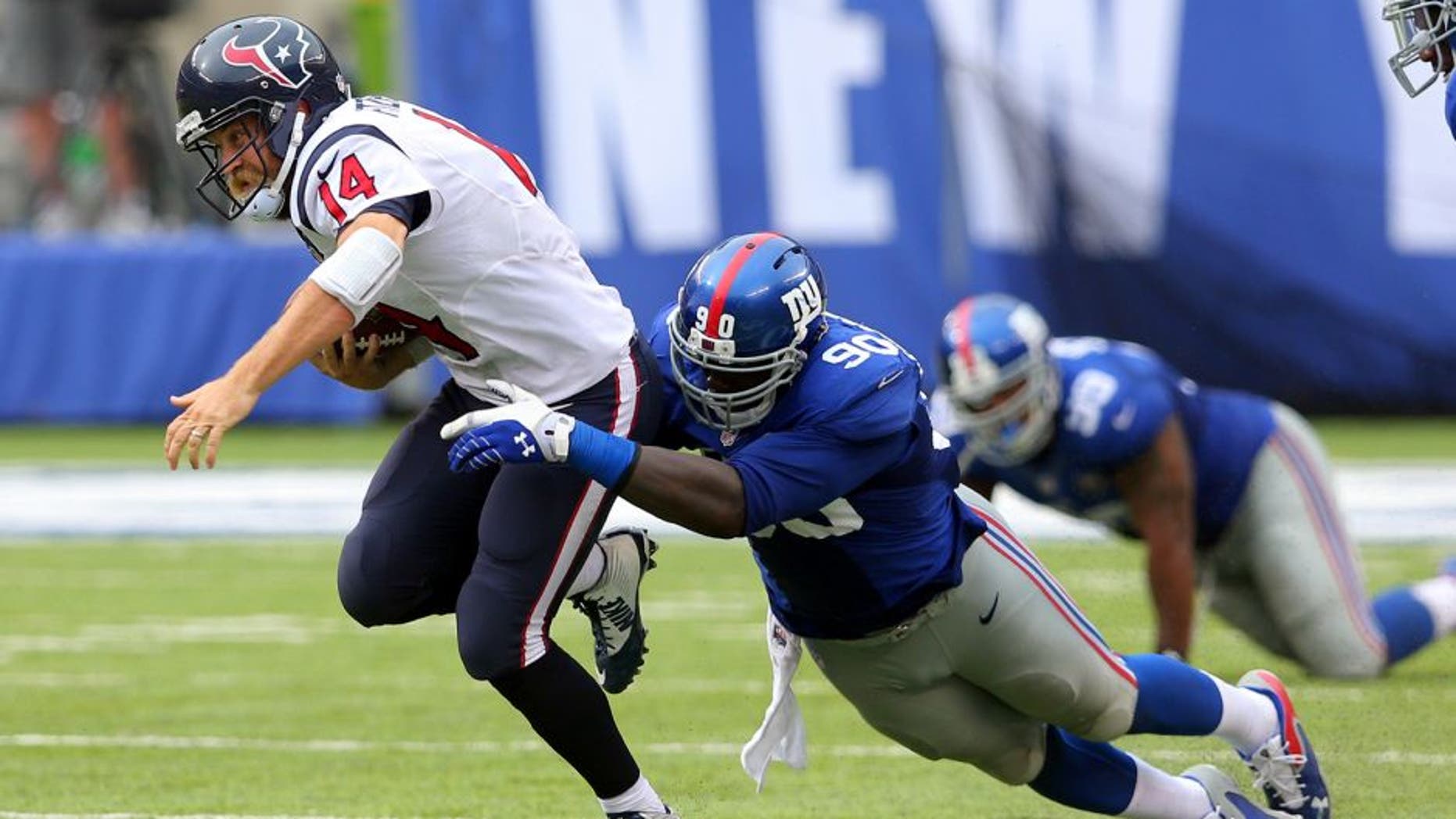 Sep 21, 2014; East Rutherford, NJ, USA; Houston Texans quarterback Ryan Fitzpatrick (14) is brought down by New York Giants defensive end Jason Pierre-Paul (90) during the fourth quarter at MetLife Stadium. Mandatory Credit: Brad Penner-USA TODAY Sports