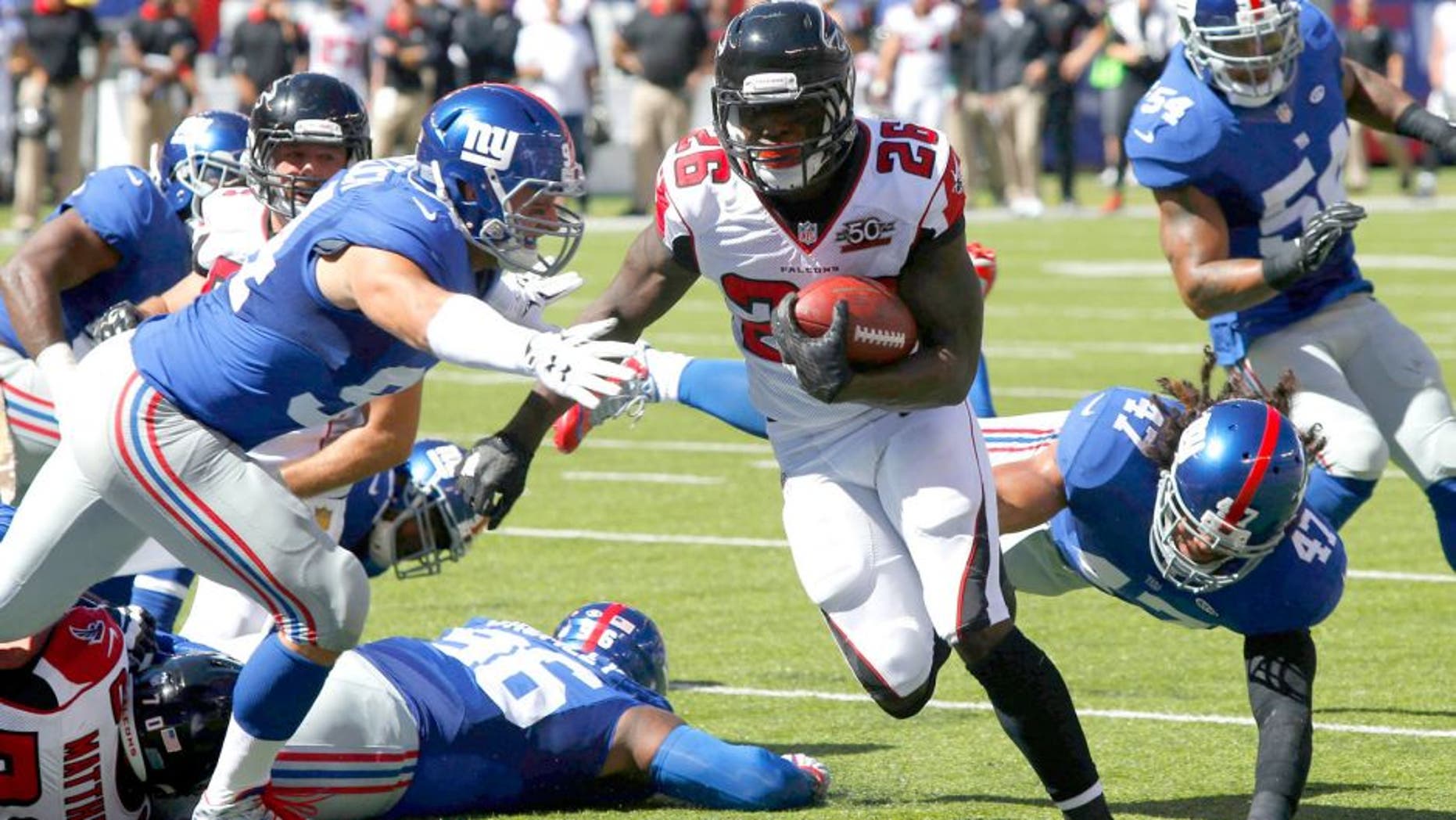 Sep 20, 2015; East Rutherford, NJ, USA; Atlanta Falcons running back Tevin Coleman (26) runs by New York Giants outside linebacker Mark Herzlich (94) and New York Giants middle linebacker Uani' Unga (47) for a touchdown during first half at MetLife Stadium. Mandatory Credit: Noah K. Murray-USA TODAY Sports