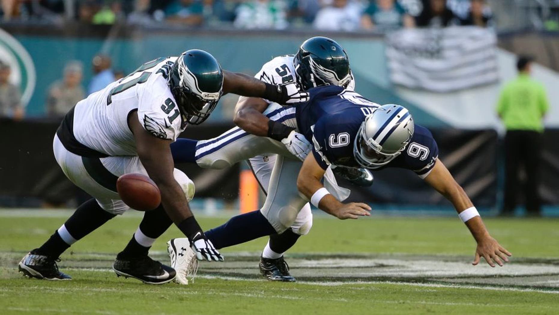 Dallas Cowboys' Tony Romo (9) fumbles the football against Philadelphia Eagles' Fletcher Cox (91) and Jordan Hicks (58) during the second half of an NFL football game, Sunday, Sept. 20, 2015, in Philadelphia. (AP Photo/Matt Rourke)