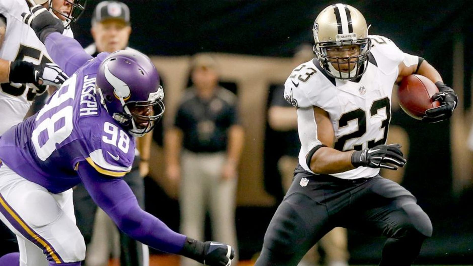 Sep 21, 2014; New Orleans, LA, USA; New Orleans Saints running back Pierre Thomas (23) runs from Minnesota Vikings defensive tackle Linval Joseph (98) during the first quarter of a game at Mercedes-Benz Superdome. Mandatory Credit: Derick E. Hingle-USA TODAY Sports