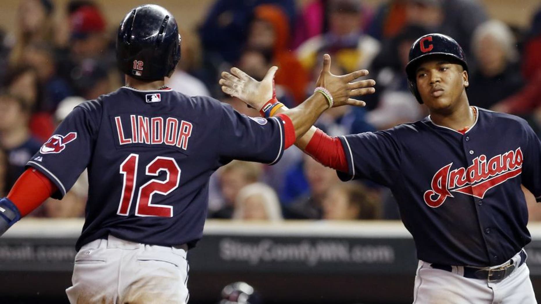 Cleveland Indians' Francisco Lindor, left, and Jose Ramirez celebrate after scoring on a two-run single by Lonnie Chisenhall off Minnesota Twins pitcher Kyle Gibson in the first inning of a baseball game, Thursday, Sept. 24, 2015, in Minneapolis.