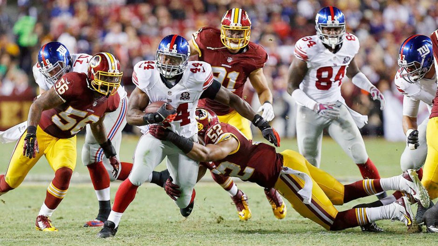 Sep 25, 2014; Landover, MD, USA; New York Giants running back Andre Williams (44) carries the ball as Washington Redskins inside linebacker Keenan Robinson (52) and Redskins inside linebacker Perry Riley (56) attempt the tackle in the third quarter at FedEx Field. The Giants won 45-14. Mandatory Credit: Geoff Burke-USA TODAY Sports