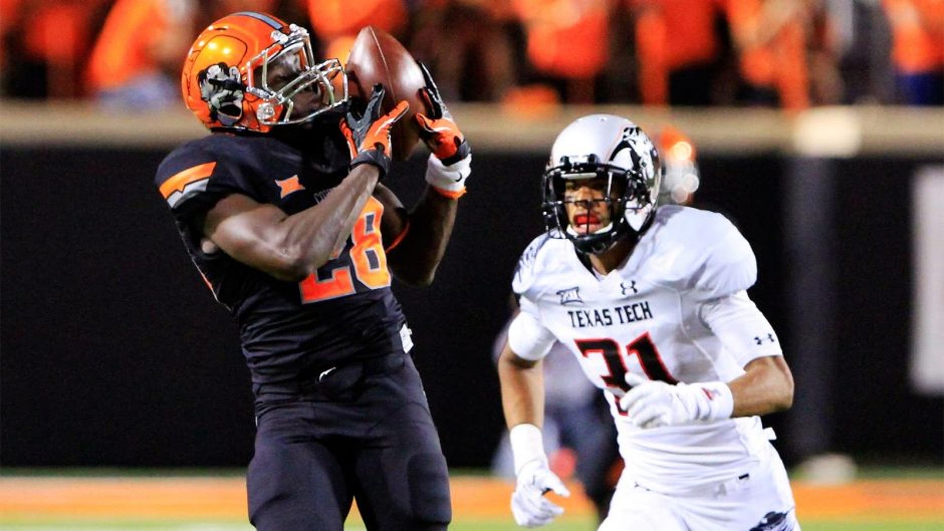 Sep 25, 2014; Stillwater, OK, USA; Oklahoma State Cowboys wide receiver James Washington (28) makes a catch in front of Texas Tech Red Raiders defensive back Justis Nelson (31) during the third quarter of a game at Boone Pickens Stadium. Oklahoma State won 45-35. Mandatory Credit: Alonzo Adams-USA TODAY Sports