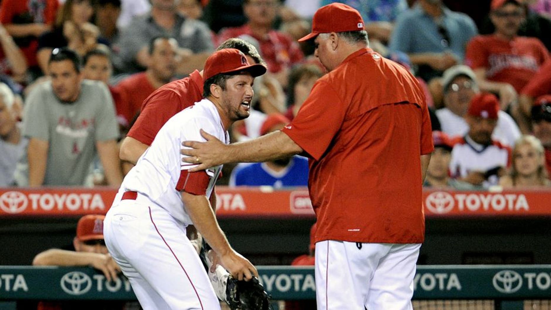 September 26, 2015; Anaheim, CA, USA; Los Angeles Angels relief pitcher Huston Street (16) reacts as he is helped by the team trainer and manager Mike Scioscia (14) after suffering an apparent injury in the ninth inning against the Seattle Mariners at Angel Stadium of Anaheim. Mandatory Credit: Gary A. Vasquez-USA TODAY Sports