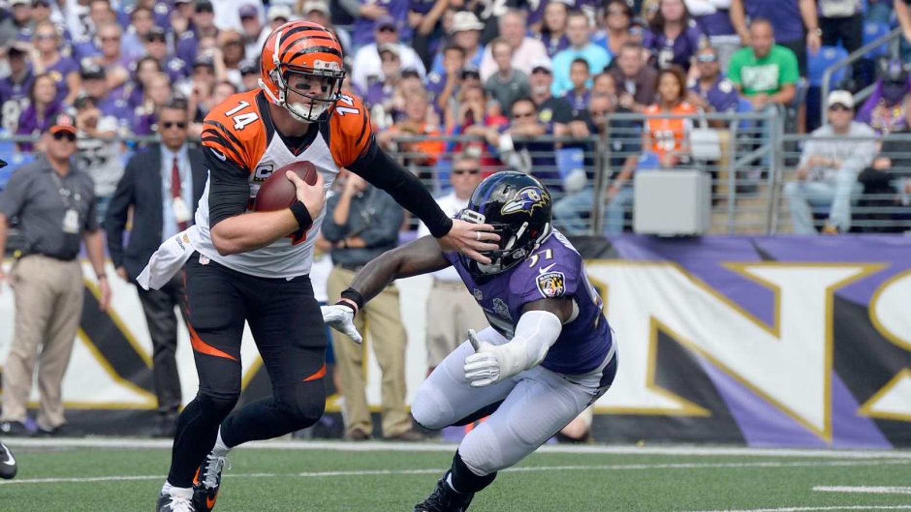 Sep 27, 2015; Baltimore, MD, USA; Cincinnati Bengals quarterback Andy Dalton (14) stiff arms Baltimore Ravens inside linebacker C.J. Mosley (57) as he run during the first quarter at M&T Bank Stadium. Mandatory Credit: Tommy Gilligan-USA TODAY Sports