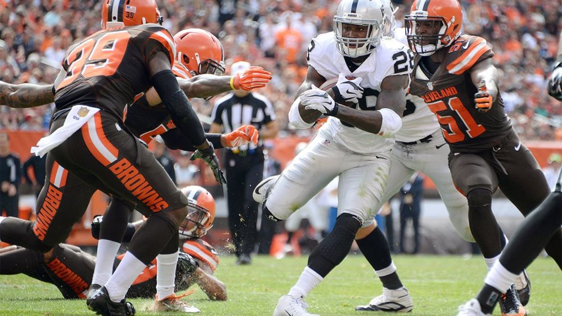 CLEVELAND, OH - SEPTEMBER 27: Latavius Murray #28 of the Oakland Raiders carries the ball between the defense of Tashaun Gipson #39 and Barkevious Mingo #51 of the Cleveland Browns during the second quarter at FirstEnergy Stadium on September 27, 2015 in Cleveland, Ohio. (Photo by Jason Miller/Getty Images)