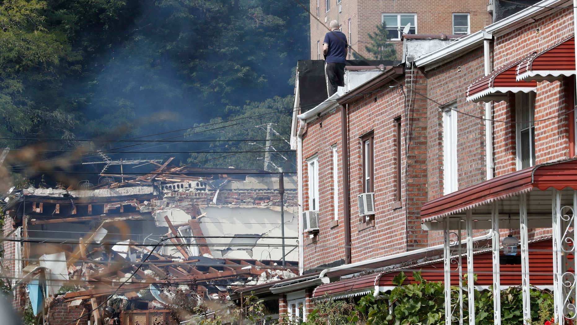 A man watches emergency service personnel work at the scene of a house explosion from a roof, Tuesday, Sept. 27, 2016, in the Bronx borough of New York.