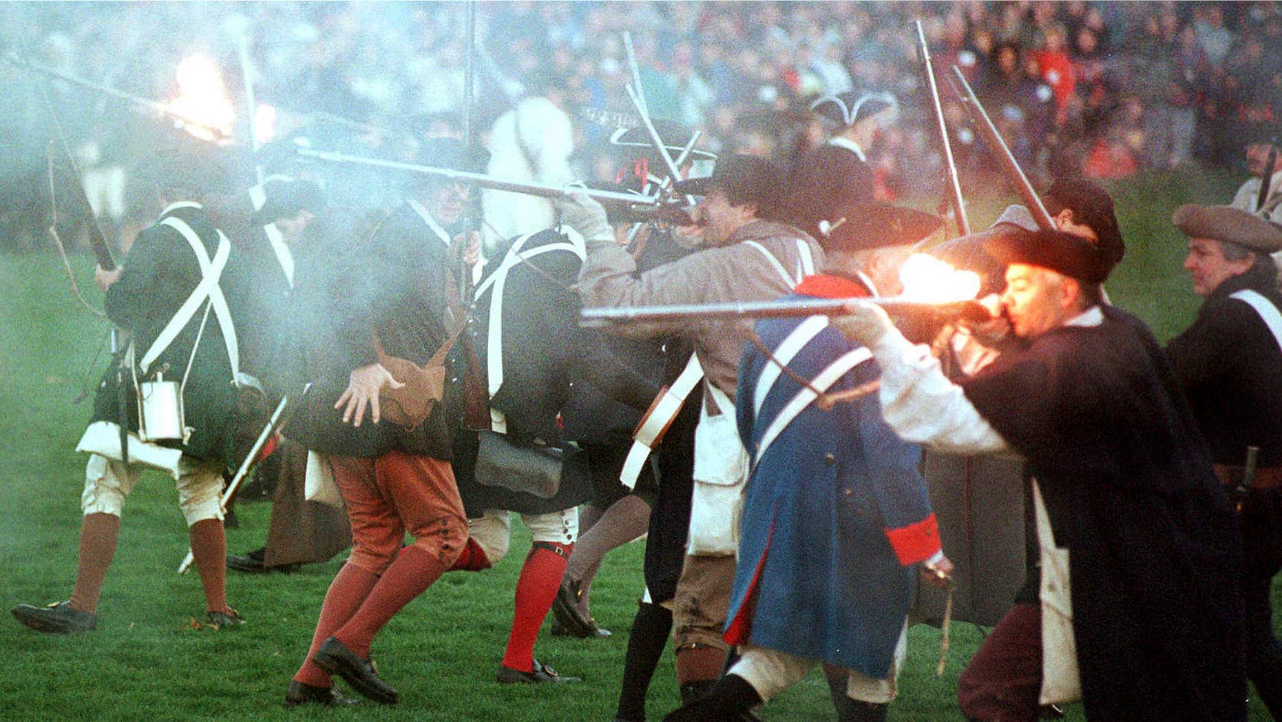 FILE - In this April 15, 2000, file photo, Revolutionary War re-enactors portraying colonial militiamen fire on British regular soldiers in the Battle of Lexington on the Lexington Green in Lexington, Mass.
