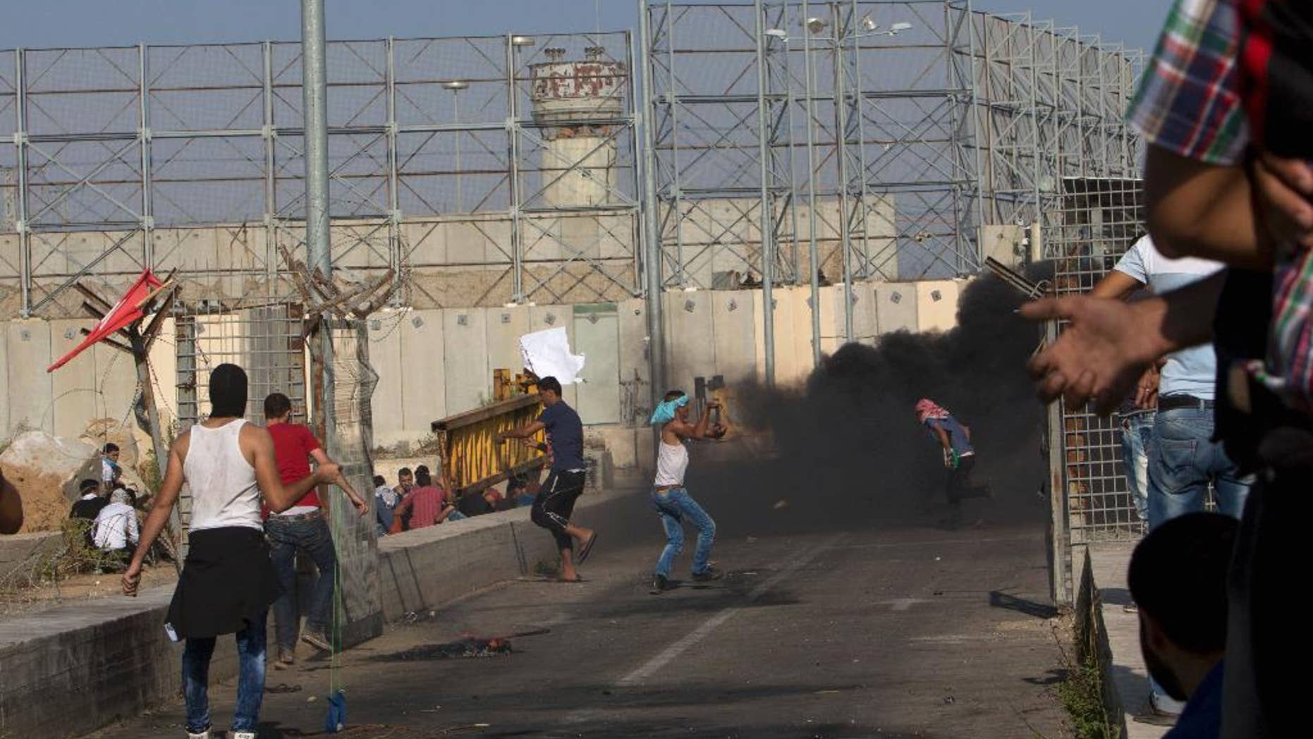 FILE - In this Oct. 16, 2015 file photo, Palestinian demonstrators hurl stones at Israeli soldiers during clashes at the entrance of Erez border crossing between the Gaza Strip and Israel, in the northern Gaza Strip. An Israeli advocacy group is reporting a sharp jump in the number of Palestinians from the Gaza Strip who have been summoned for questioning by Israeli security agents as a condition for leaving the blockaded territory. Gisha, which pushes for freedom of movement for Gaza’s 1.8 million people, says more than 1,200 Gazans underwent interrogations during the first half of this year. (AP Photo/Adel Hana, File)