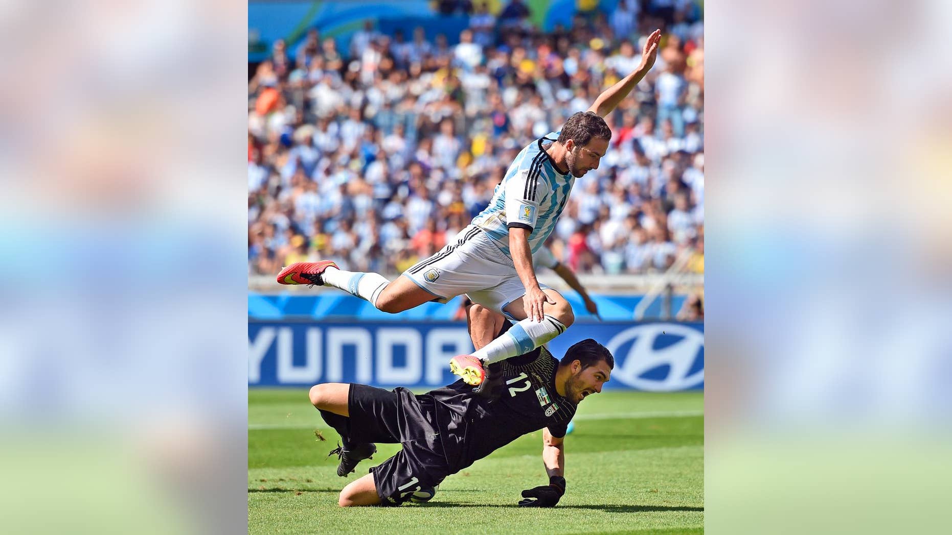 Argentina's Gonzalo Higuain leaps over Iran's goalkeeper Alireza Haghighi after taking a shot on goal during the group F World Cup soccer match between Argentina and Iran at the Mineirao Stadium in Belo Horizonte, Brazil, Saturday, June 21, 2014. (AP Photo/Martin Meissner)