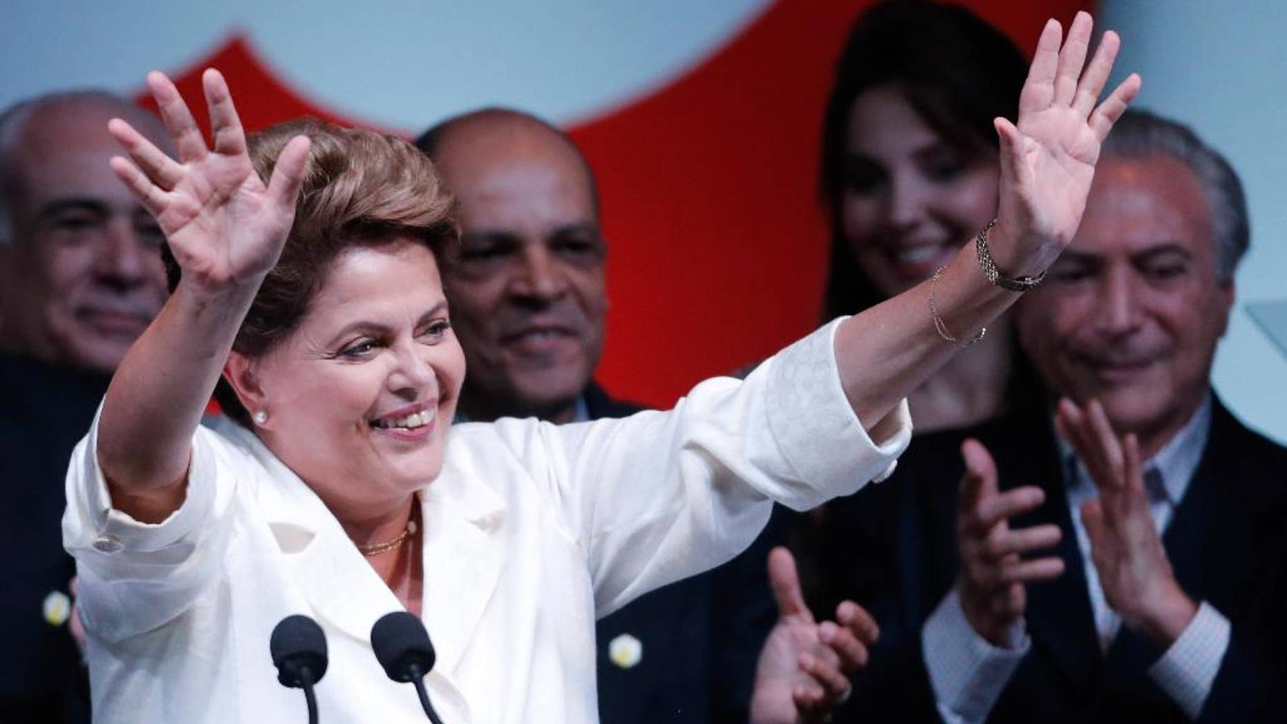 Brazil's President Dilma Rousseff, raises her arms to acknowledge the crowd during her acceptance speech at a press conference in a hotel in Brasilia, Brazil, Sunday, Oct. 26, 2014. Official results showed Sunday that President Rousseff defeated opposition candidate Aecio Neves of the Brazilian Social Democracy Party, and was re-elected Brazil's president. (AP Photo/Eraldo Peres)