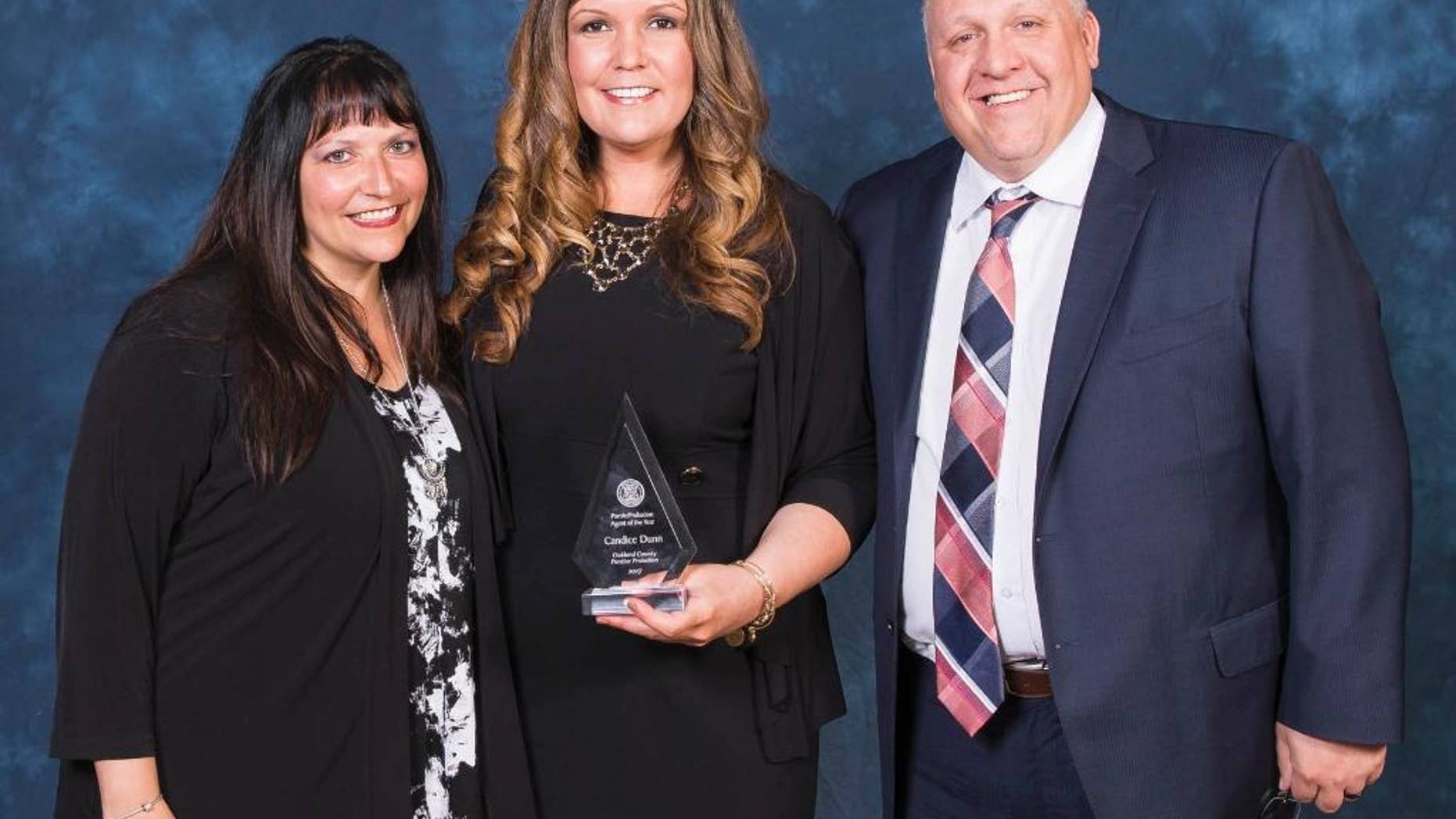 In this Tuesday, March 9, 2017 photo, provided by the Michigan Department of Corrections, Candice Dunn, center, stands with employees Heather Wayne and Brock Dietrich after receiving the state's parole/probation agent of the year award in East Lansing, Mich. Dunn was one of five people killed in a car crash Tuesday, May 9, in Livingston County. (Michigan Department of Corrections via AP)